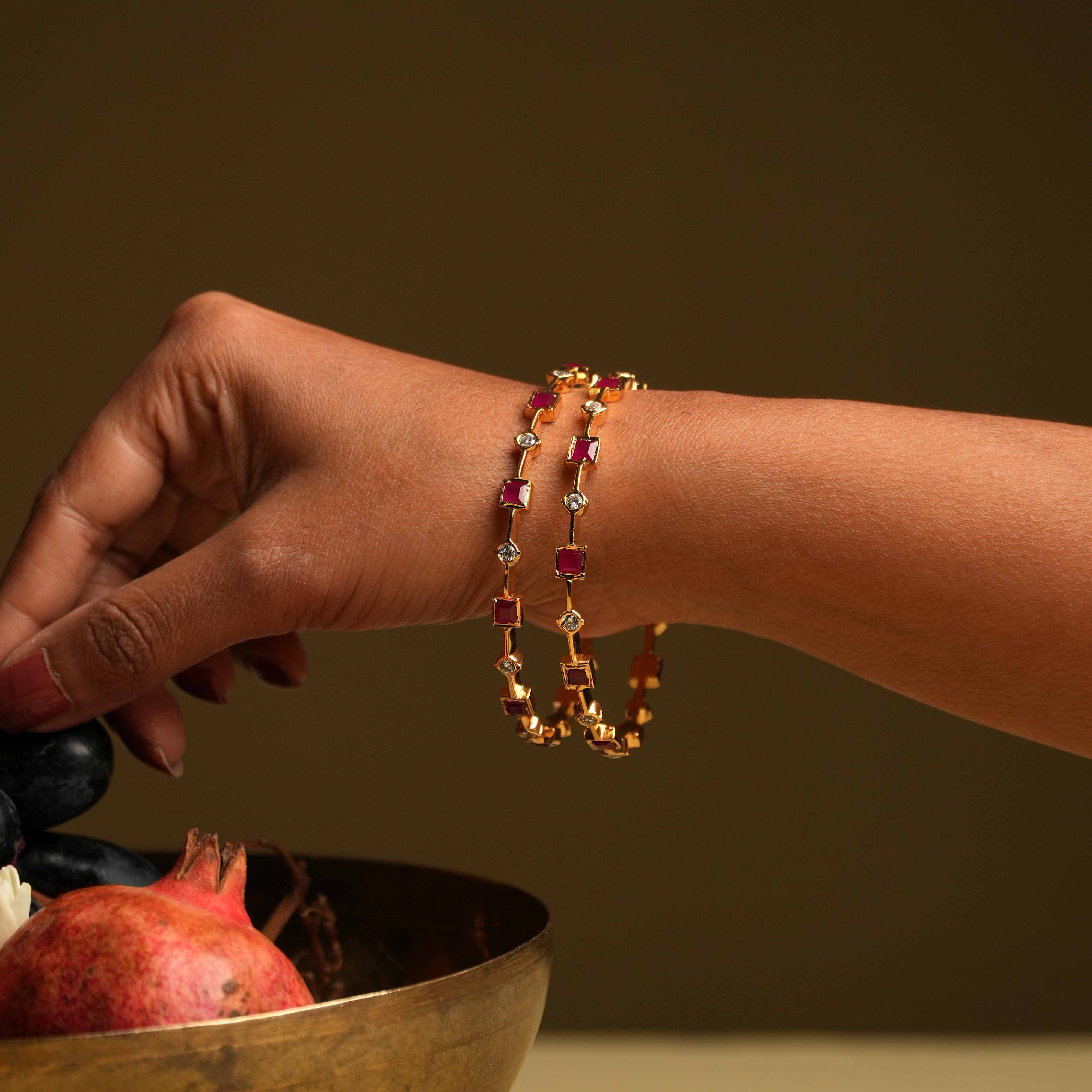 A minimalist 92.5 sterling silver bangle with an insert type closure, featuring alternating square-cut red gemstones and round white stones, creating a delicate dance of color and light, perfect for the woman who values sleek sophistication and a touch of subtle glamour.