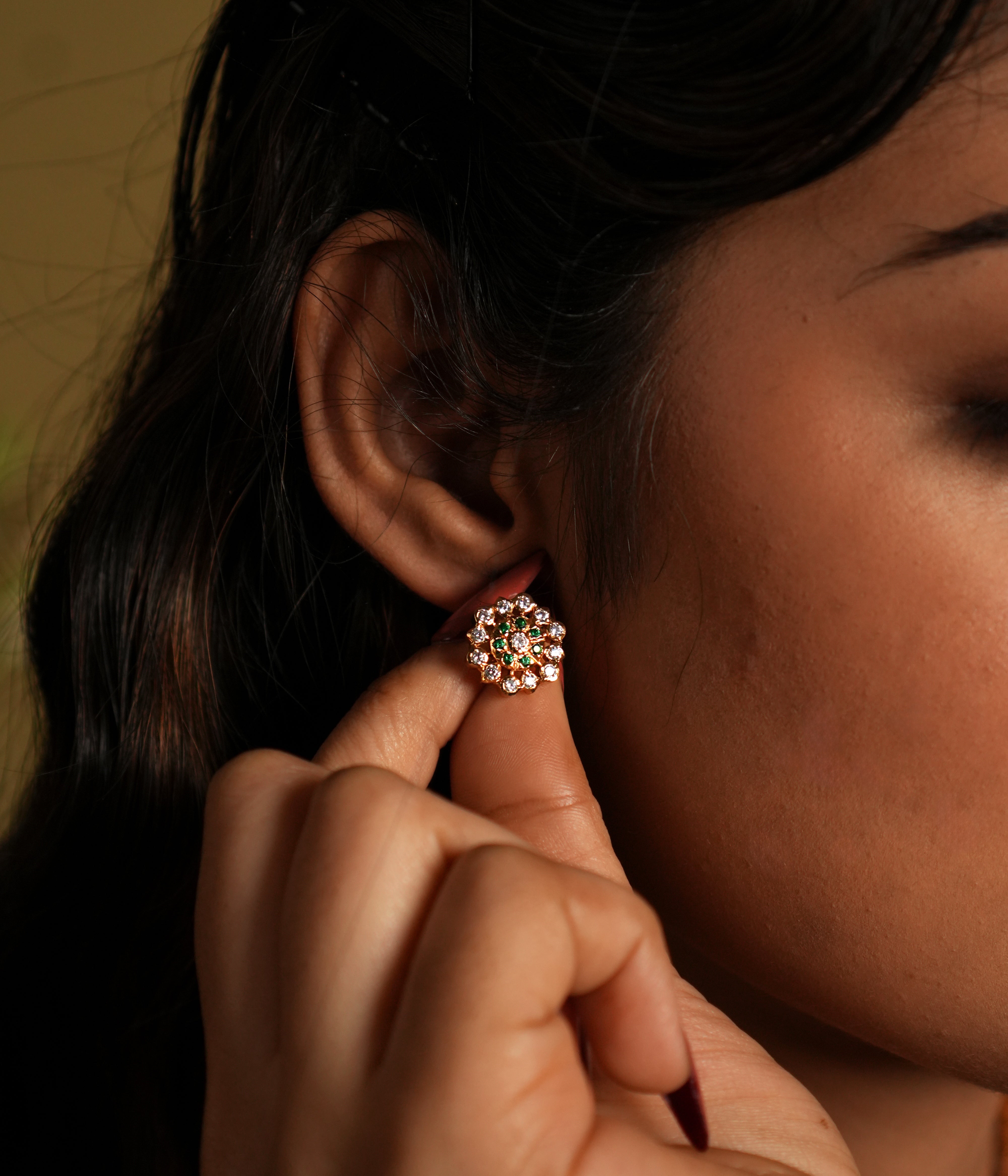 This image showcases a pair of elegant stud earrings crafted from 92.5 sterling silver and adorned with Swarovski stones. The earrings feature a gold-plated finish, adding a touch of sophistication and luxury to their design.