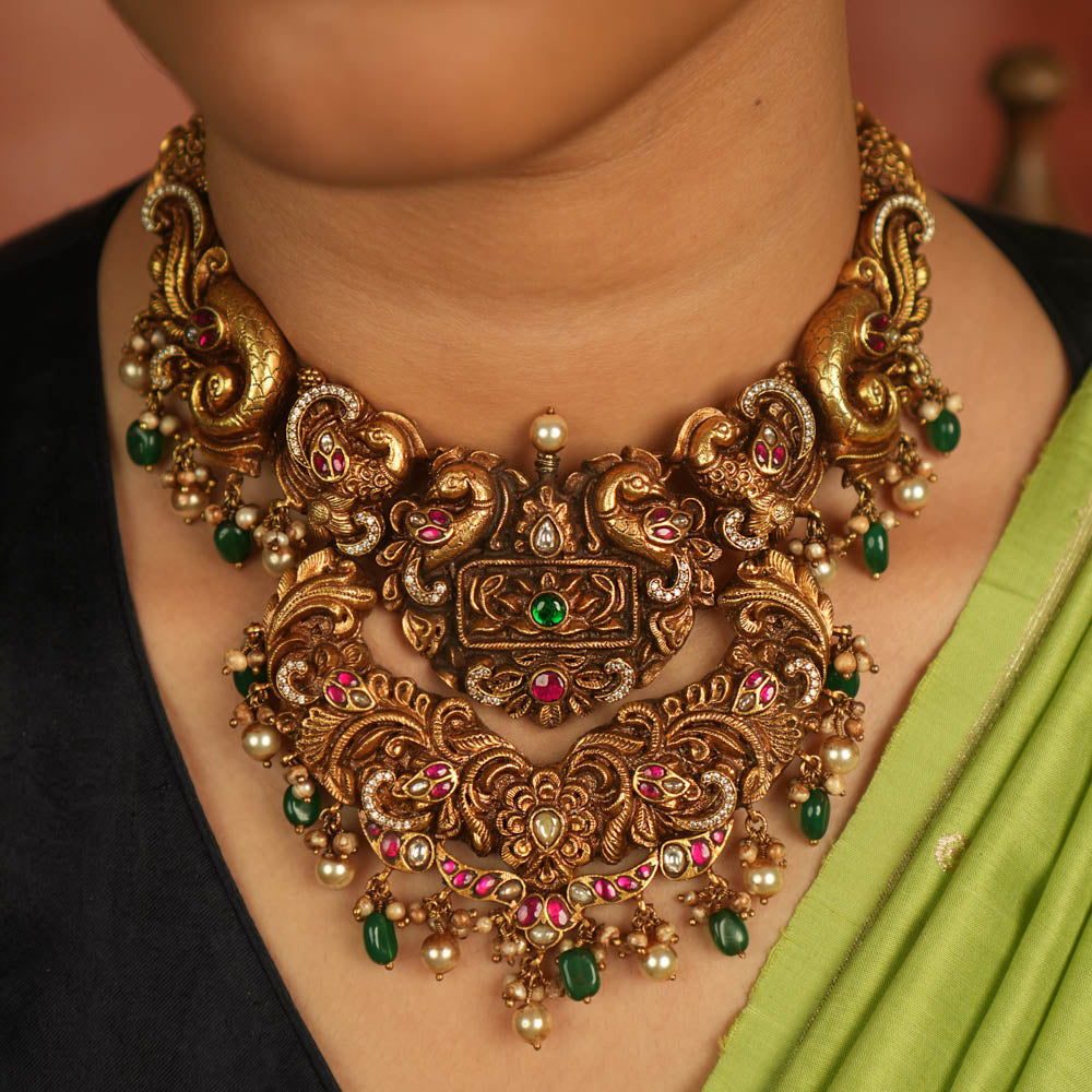 Temple whispers reborn! Antique gold necklace adorned with peacock and floral motifs, where kundan, pearls, and green beads evoke divine splendor and timeless elegance.