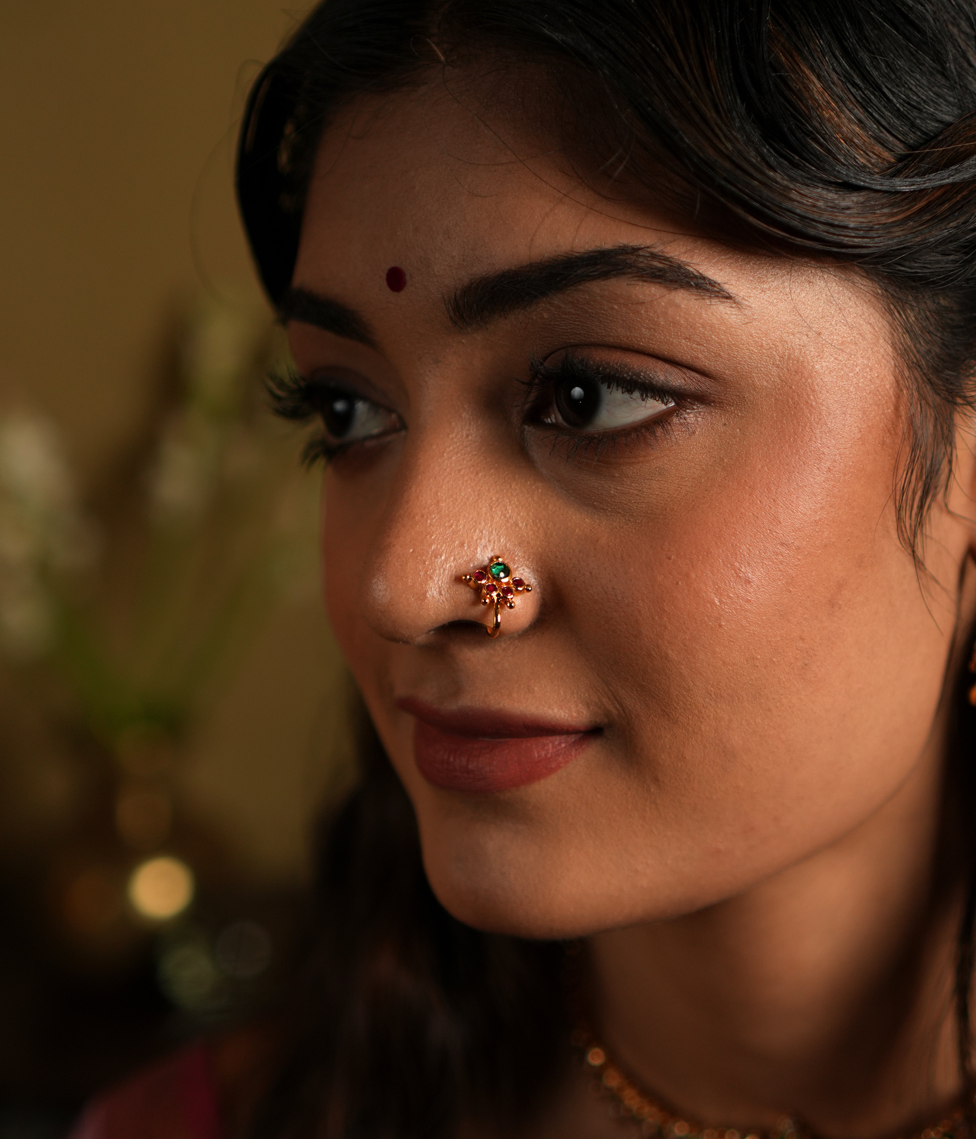 This image features a beautifully crafted 92.5 sterling silver nose pin with an elegant gold-plated finish. The nose pin is designed in a delicate floral pattern, with a striking green stone at its center, adding a subtle yet captivating charm.