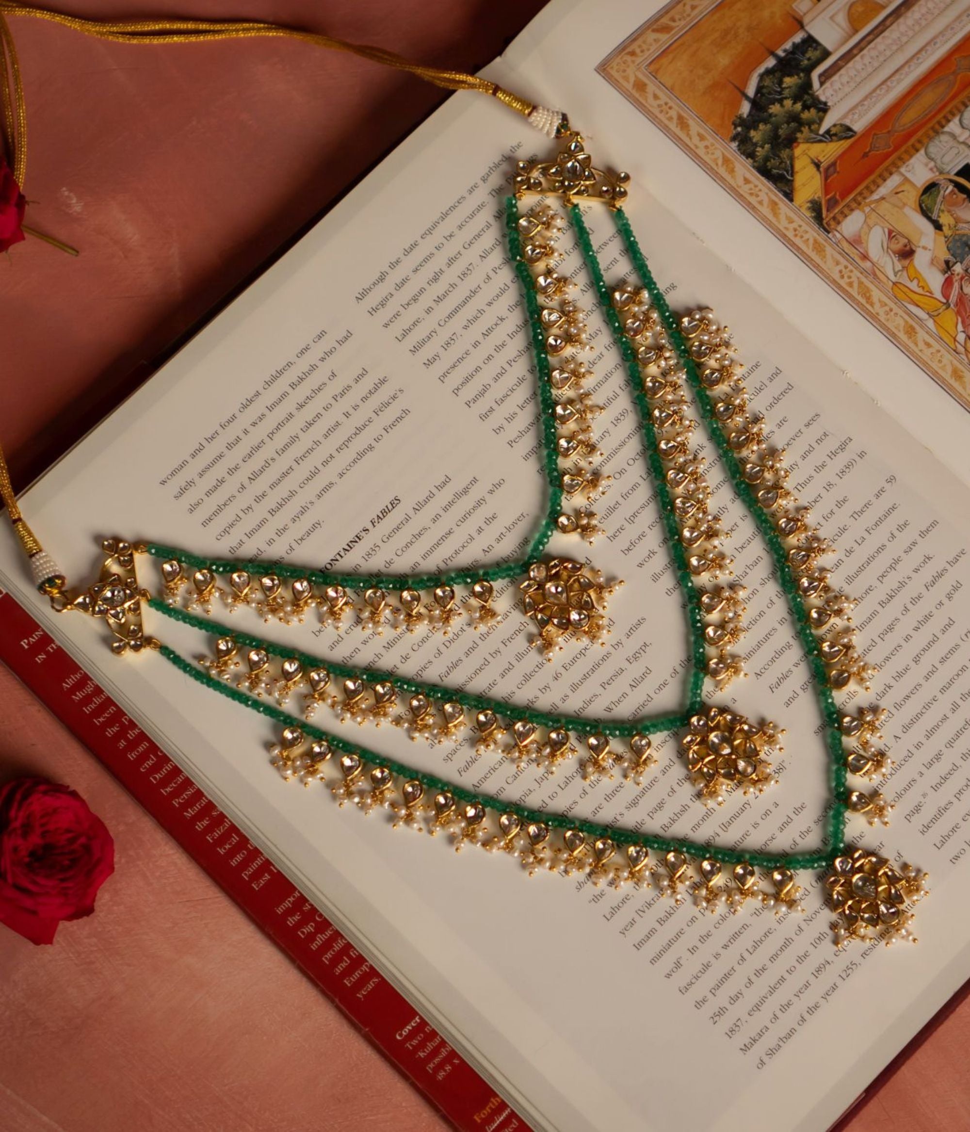 Elegant gold-plated silver necklace featuring layers of vibrant green beads intertwined with intricate white sapphires and pearl embellishments. The necklace showcases three floral-shaped pendants adorned with shimmering white sapphire stones, exuding a regal and traditional charm.