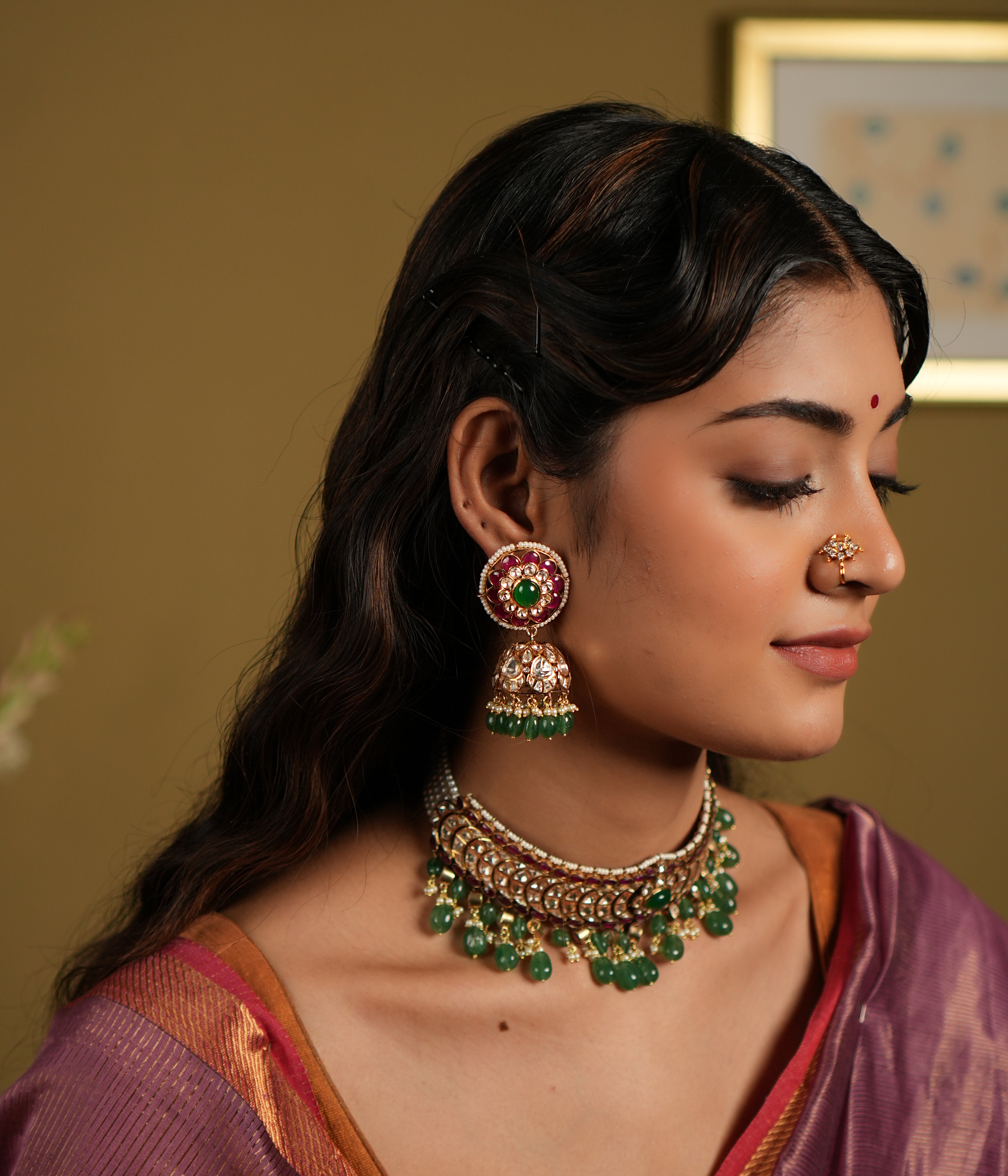 This image showcases an exquisite pair of Moissanite Polki Jhumkas crafted from 92.5 sterling silver and finished with a luxurious gold plating. The earrings feature a vibrant combination of deep red and green stones, with intricate Polki work that exudes traditional elegance.