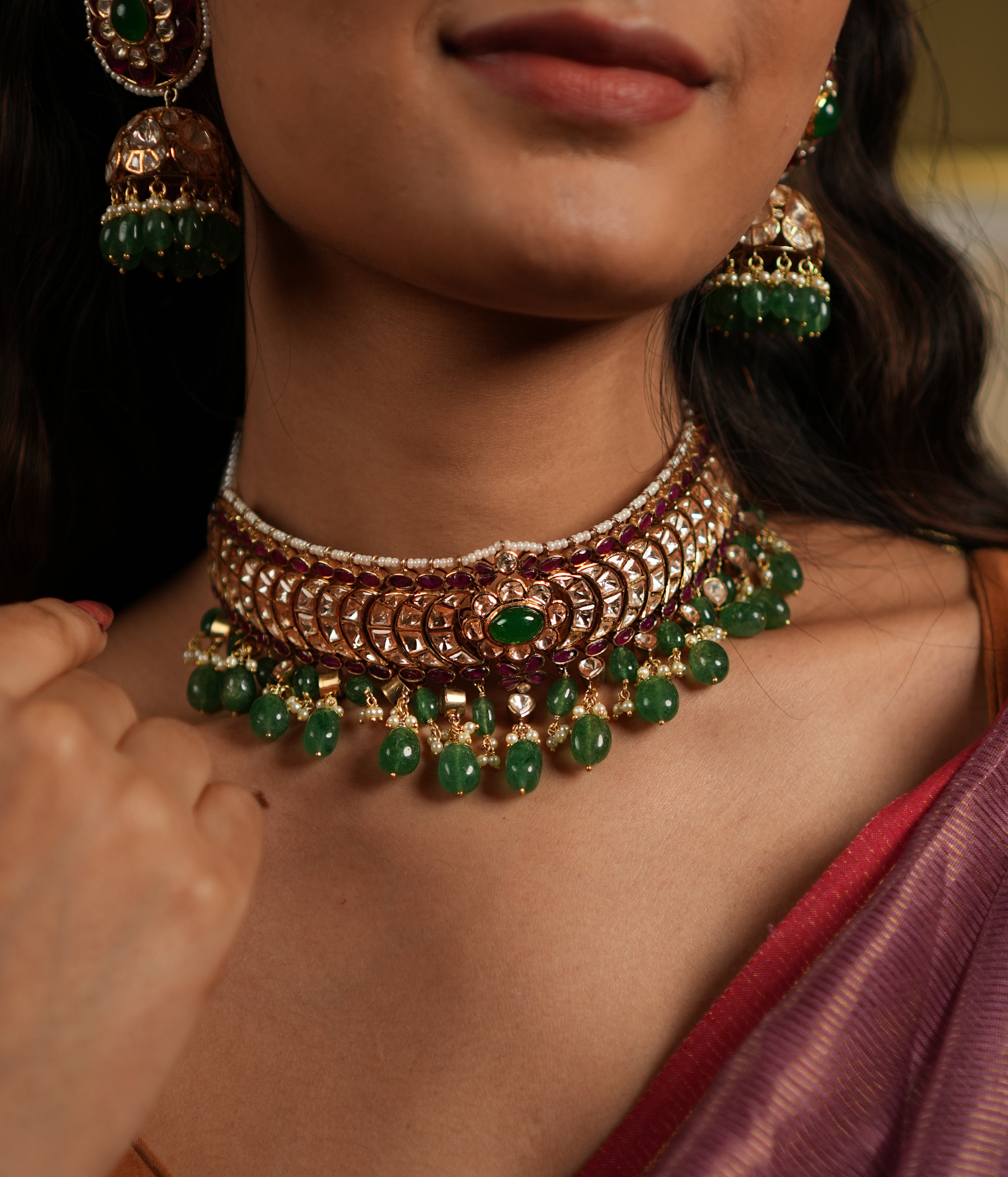 features a stunning 92.5 sterling silver choker with an exquisite gold-plated finish. The choker is adorned with moissanite polkis and vibrant green beads, creating a perfect blend of traditional elegance and modern sophistication. Its intricate craftsmanship and detailed design make it an ideal statement piece for weddings, festive occasions