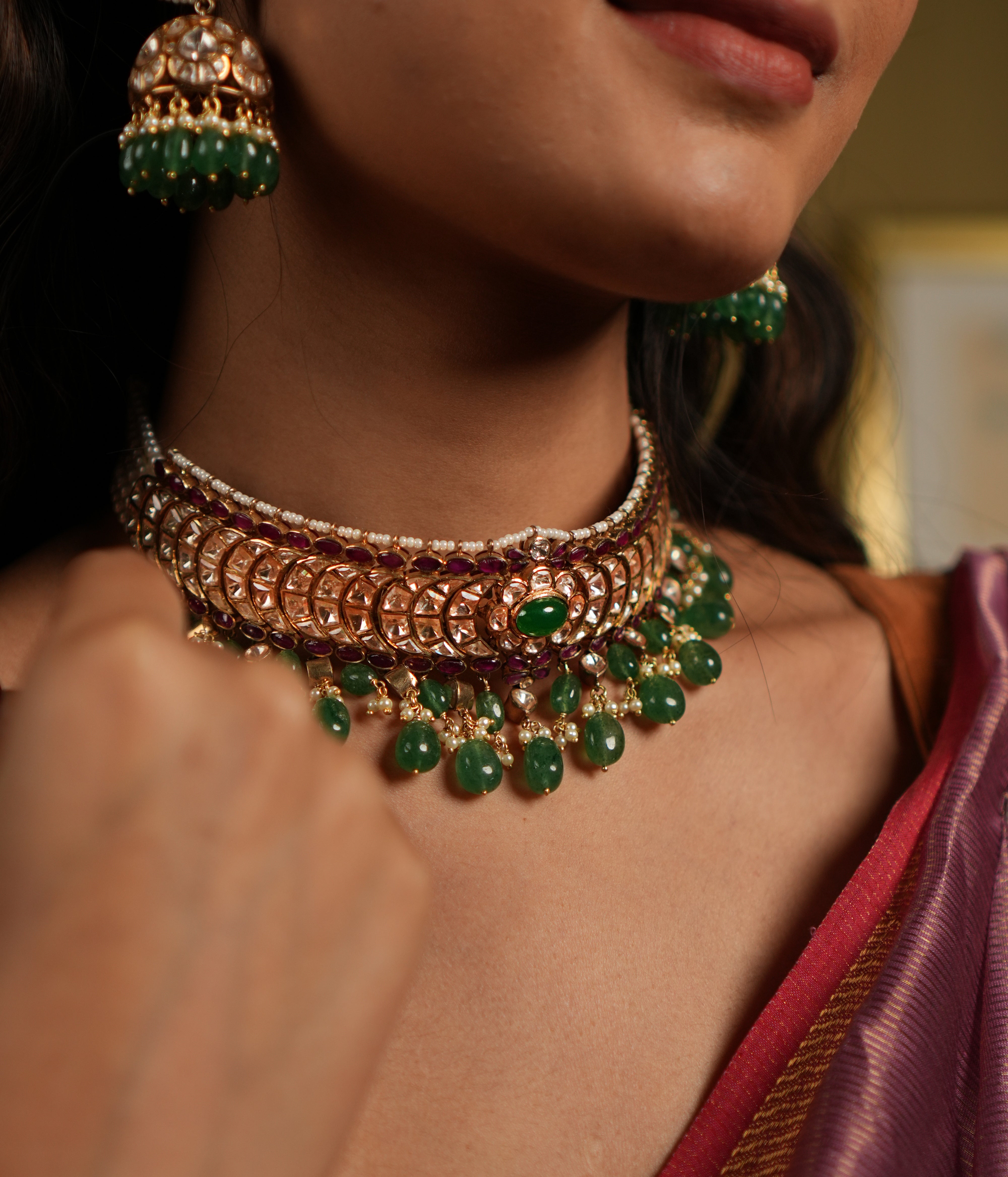 features a stunning 92.5 sterling silver choker with an exquisite gold-plated finish. The choker is adorned with moissanite polkis and vibrant green beads, creating a perfect blend of traditional elegance and modern sophistication. Its intricate craftsmanship and detailed design make it an ideal statement piece for weddings, festive occasions