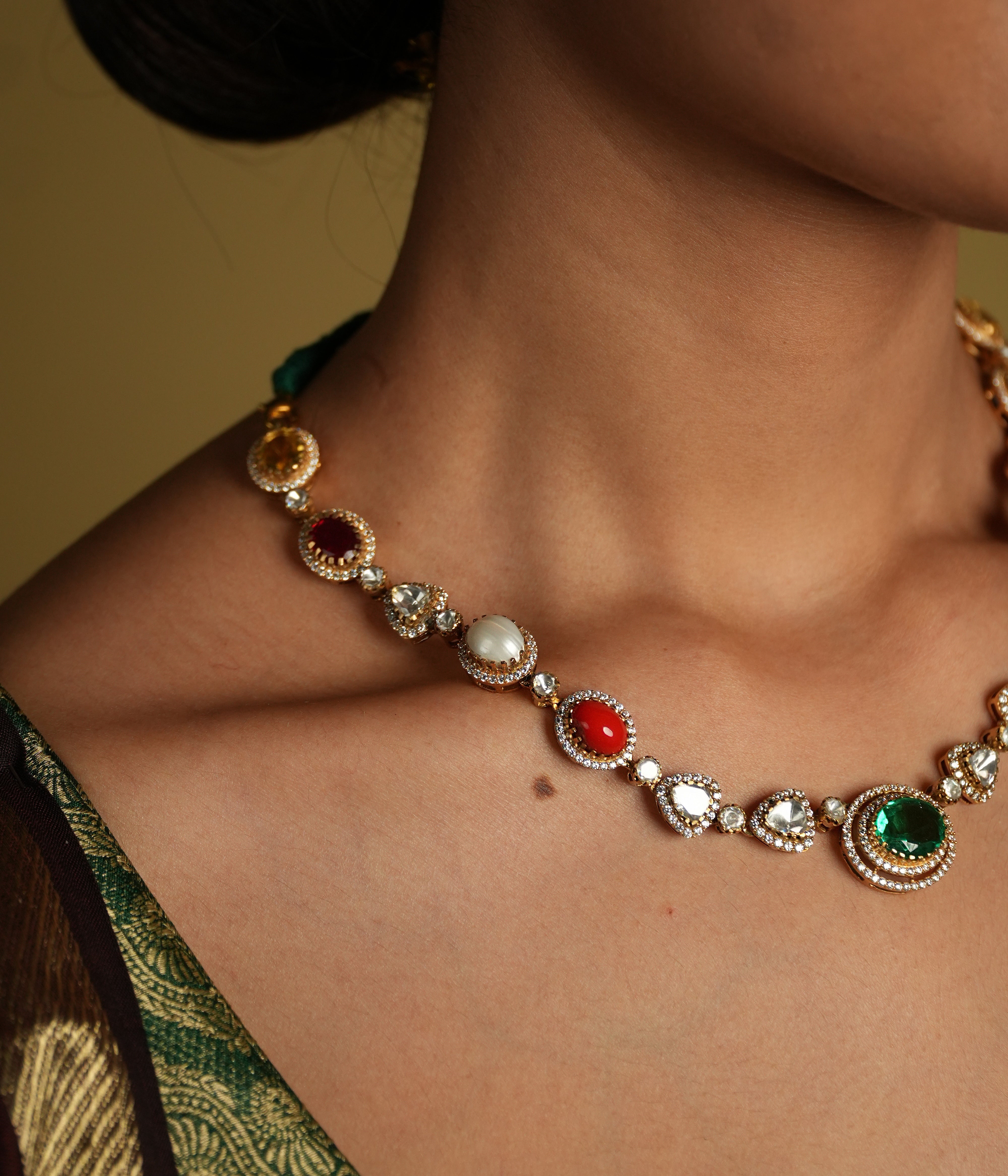 This elegant 92.5 sterling silver necklace is beautifully gold-plated and features a classic Navratna design. Adorned with nine vibrant gemstones, including emerald, ruby, sapphire, coral, and more, each stone represents celestial significance and brings a pop of color to your ensemble