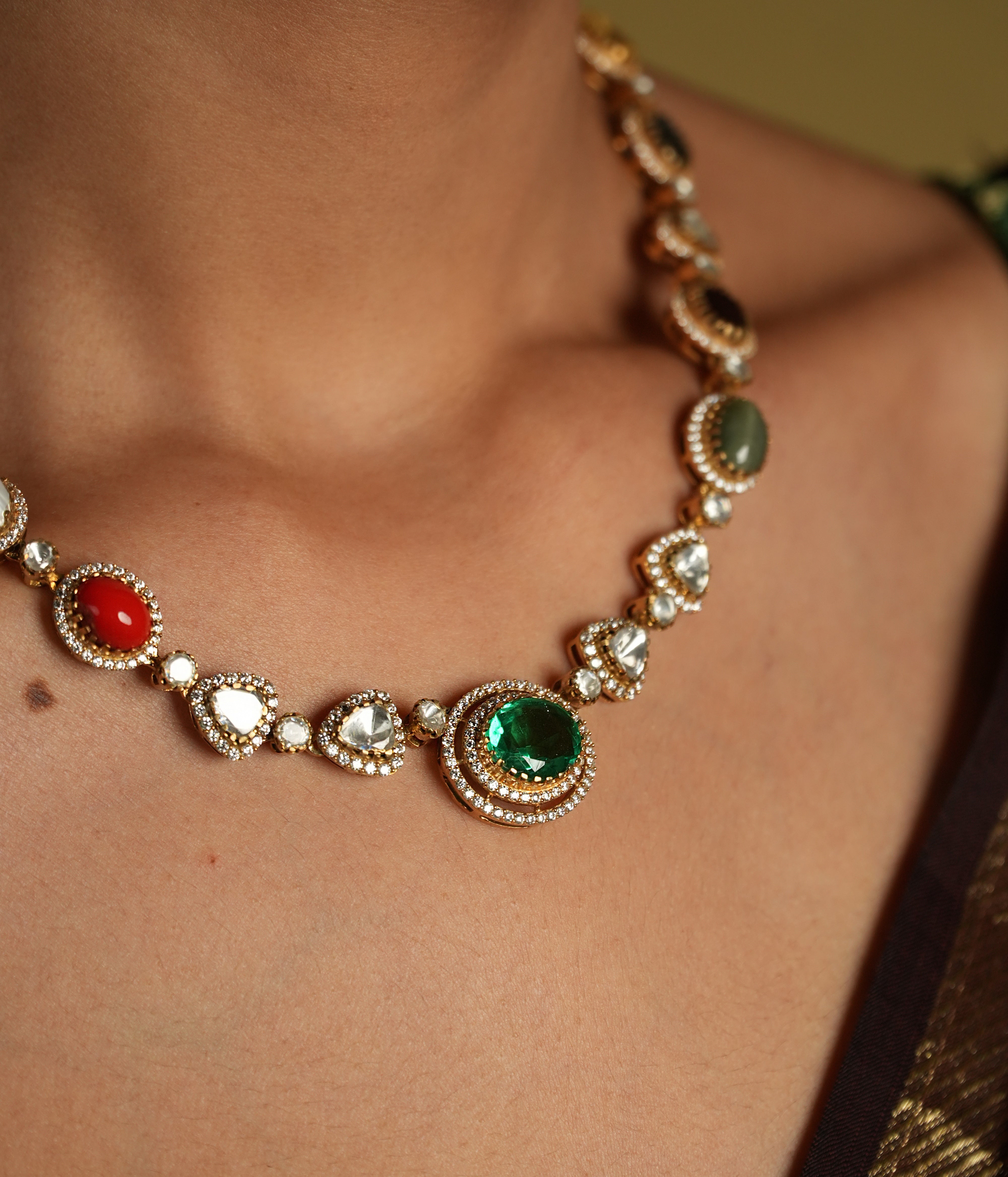 This elegant 92.5 sterling silver necklace is beautifully gold-plated and features a classic Navratna design. Adorned with nine vibrant gemstones, including emerald, ruby, sapphire, coral, and more, each stone represents celestial significance and brings a pop of color to your ensemble