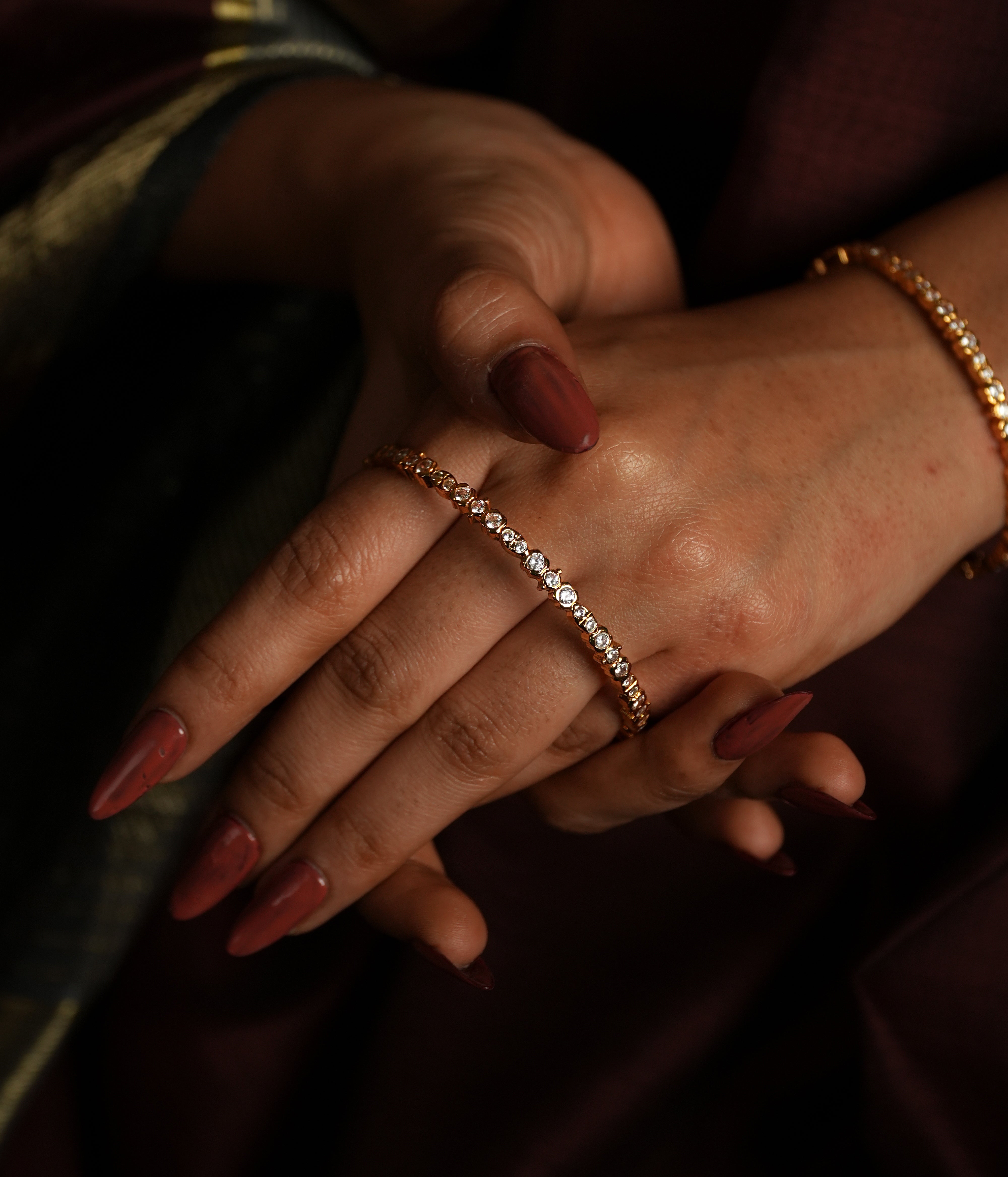 This is a close-up image of a wrist adorned with a delicate gold bracelet encrusted with swarovski Clean lines, delicate sparkle,
and heritage-inspired setting evoke the refined beauty of Tamil Nadu's iconic jewellery.
