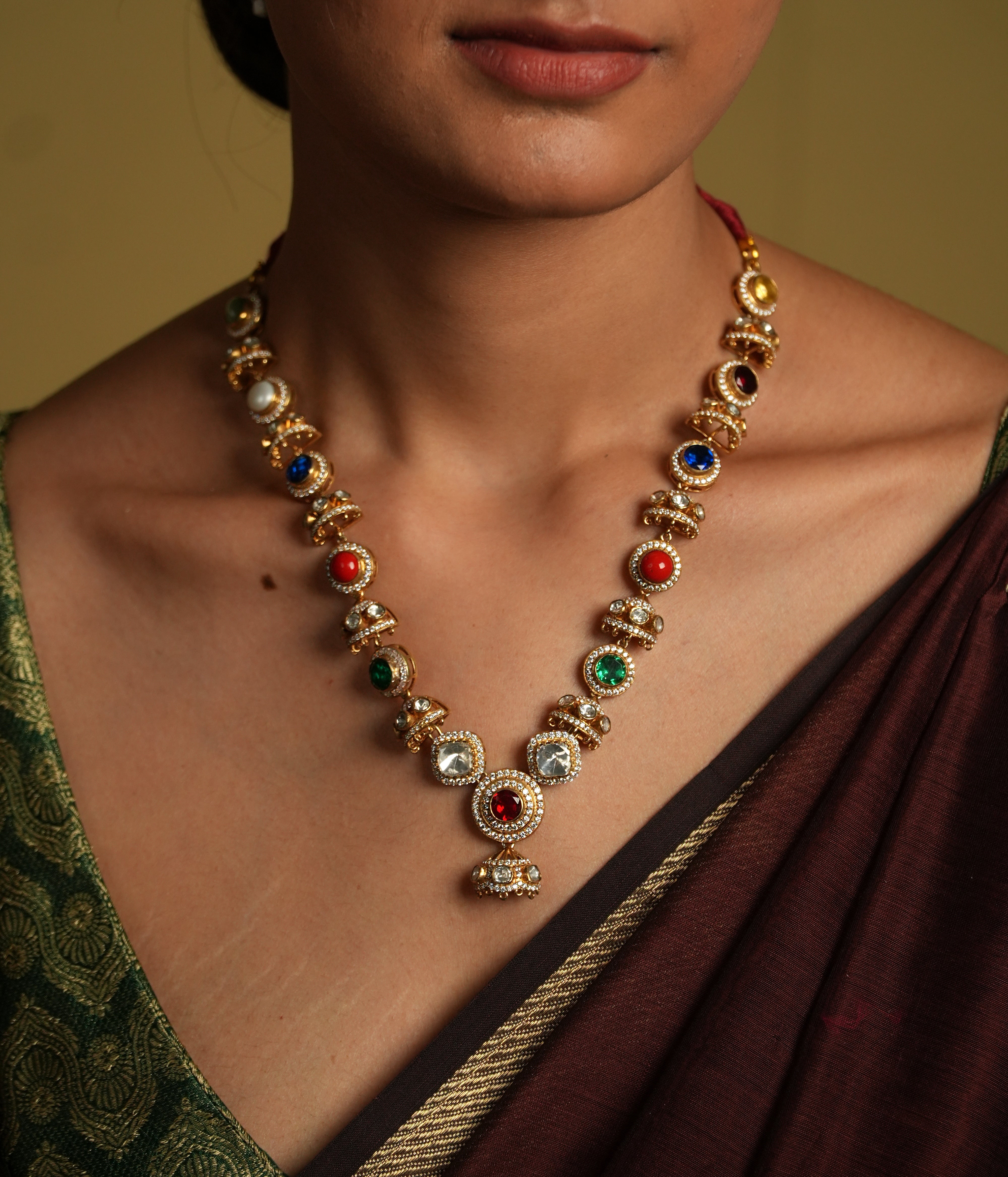 Embrace traditional elegance with this exquisite necklace, inspired by the timeless beauty of Navratan jewelry. This stunning piece features a central pendant design, likely crafted from silver with moissanite polkis and navrtana stones, gold  plated