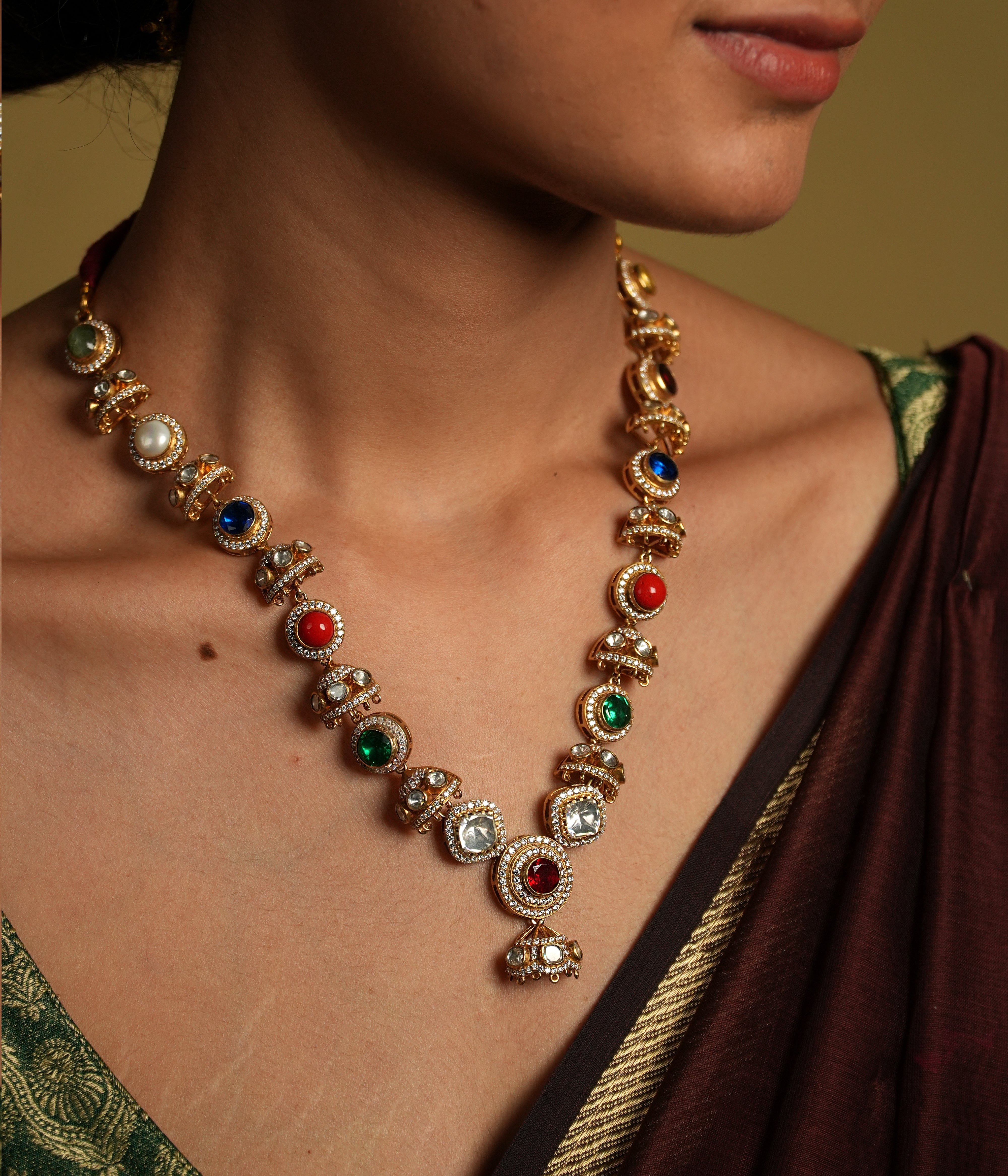 Embrace traditional elegance with this exquisite necklace, inspired by the timeless beauty of Navratan jewelry. This stunning piece features a central pendant design, likely crafted from silver with moissanite polkis and navrtana stones, gold  plated