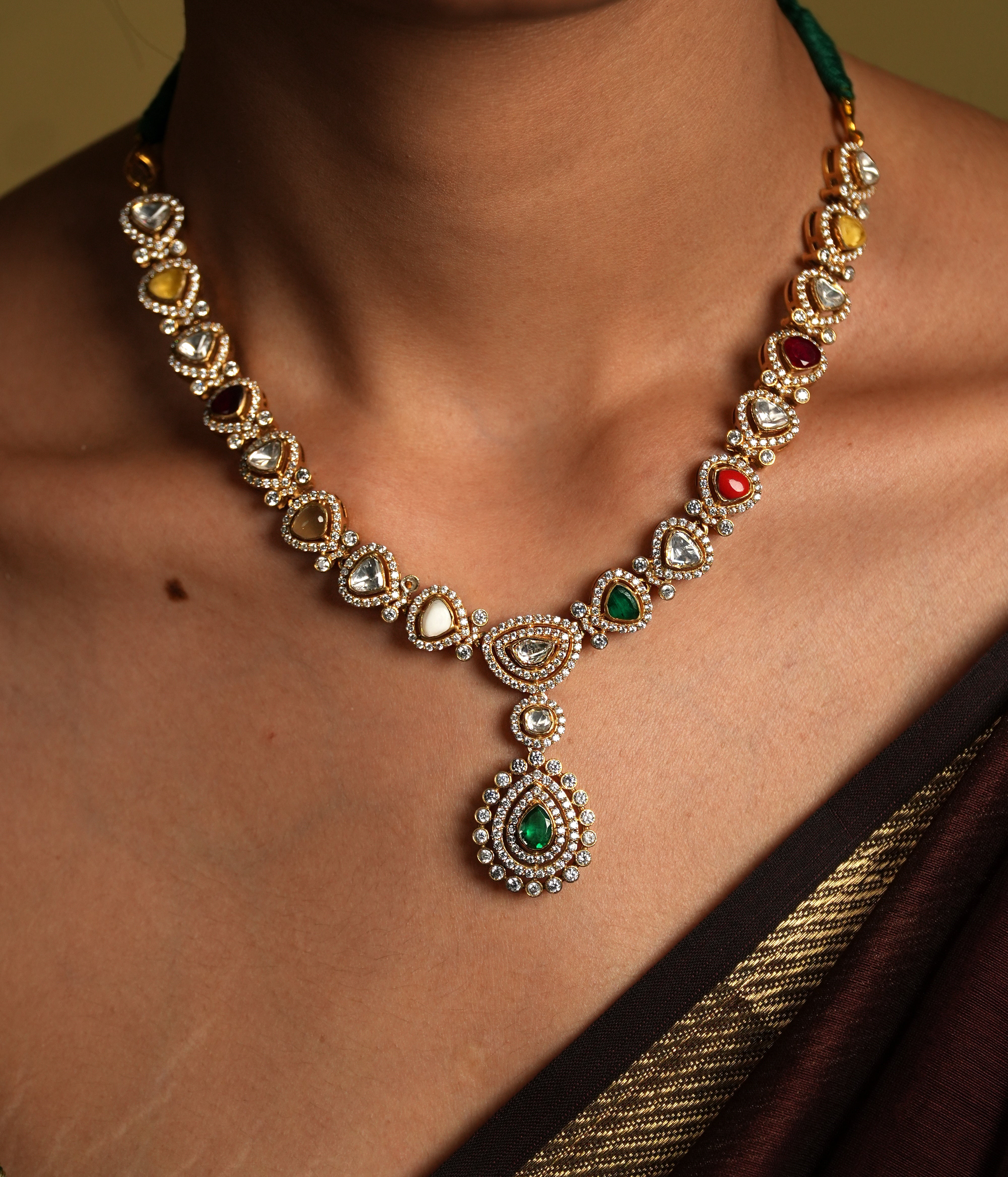 Embrace traditional elegance with this exquisite necklace, inspired by the timeless beauty of Navratan jewelry. This stunning piece features a central pendant design, likely crafted from silver with moissanite polkis and navrtana stones, gold  plated