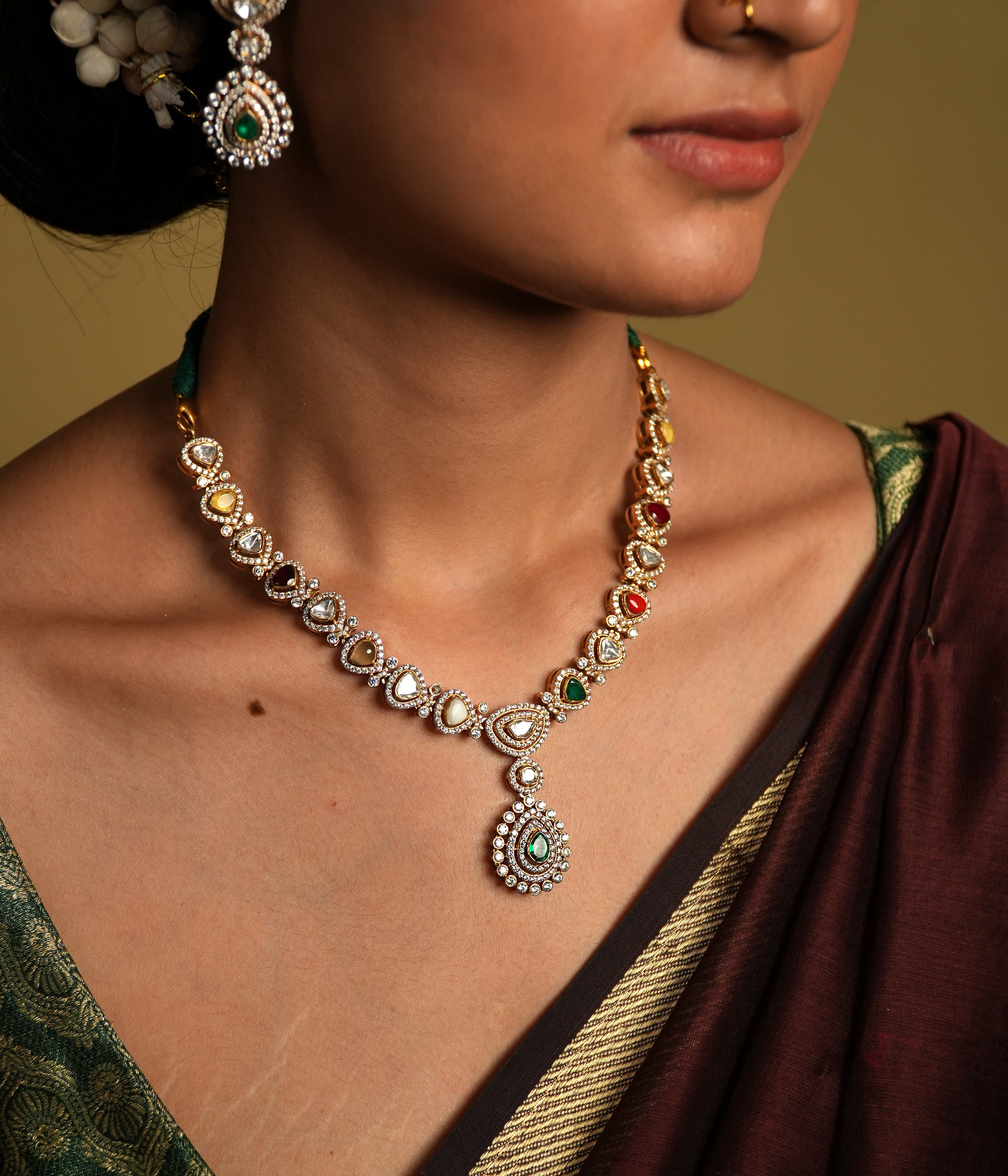 Embrace traditional elegance with this exquisite necklace, inspired by the timeless beauty of Navratan jewelry. This stunning piece features a central pendant design, likely crafted from silver with moissanite polkis and navrtana stones, gold  plated