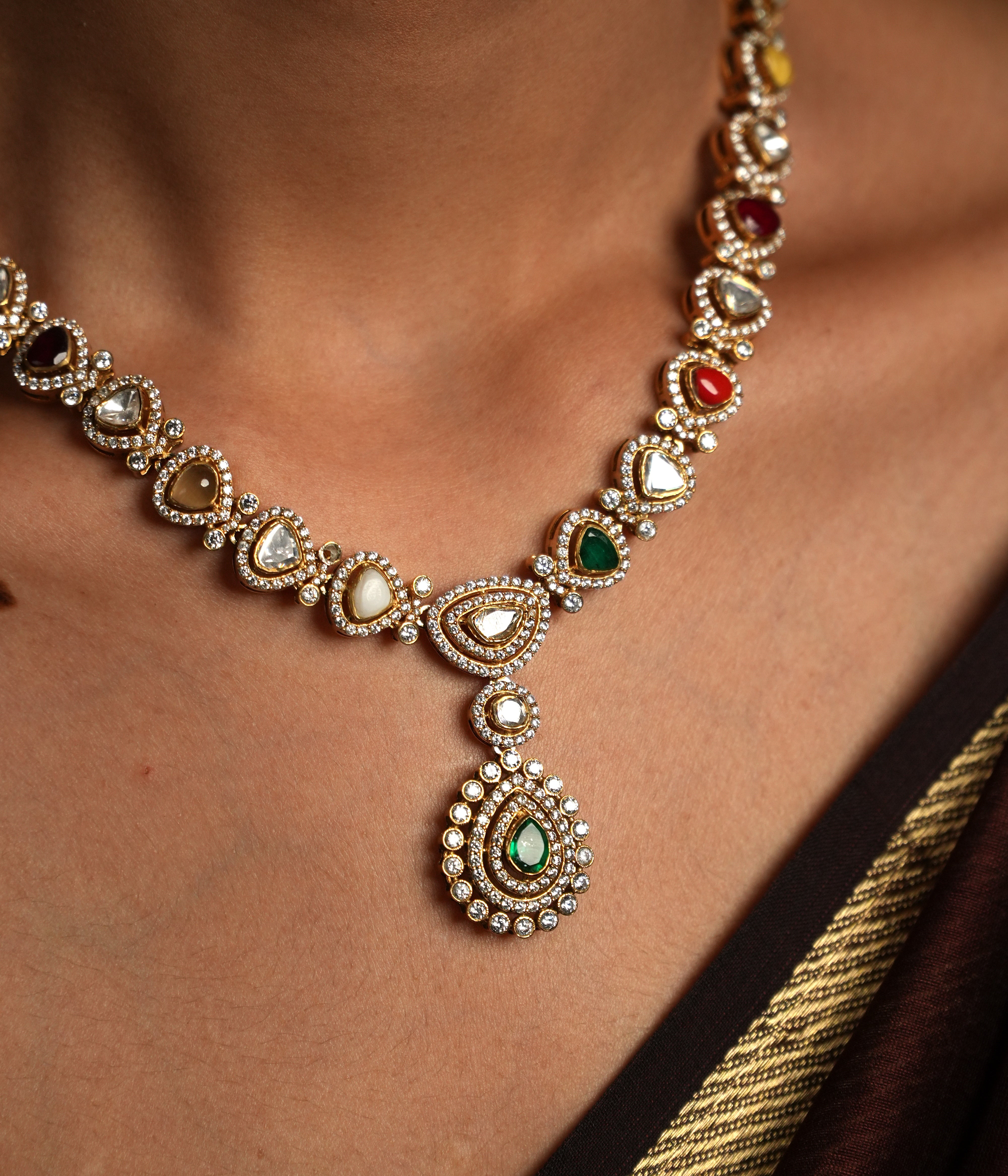 Embrace traditional elegance with this exquisite necklace, inspired by the timeless beauty of Navratan jewelry. This stunning piece features a central pendant design, likely crafted from silver with moissanite polkis and navrtana stones, gold  plated