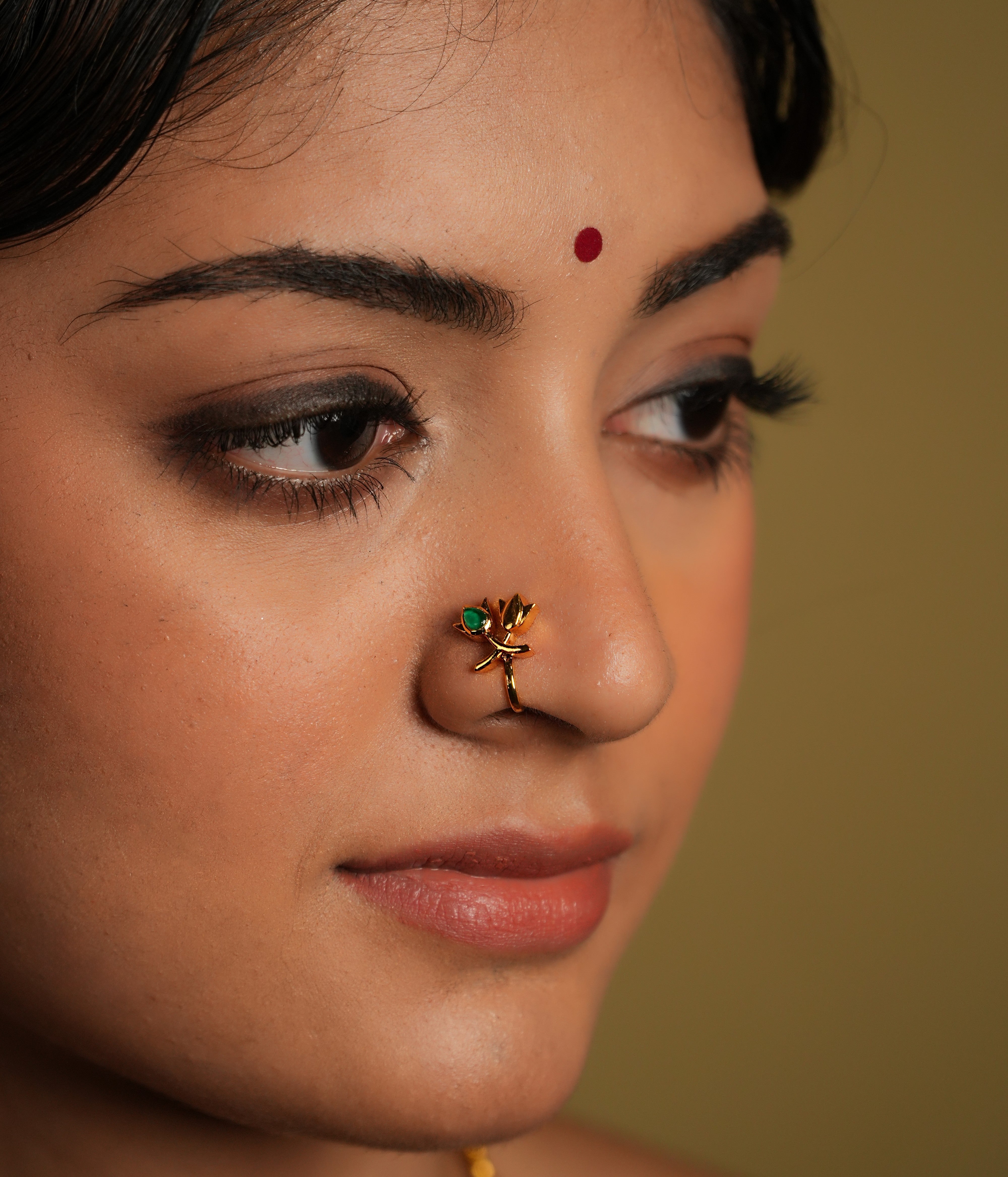 This beautiful nose pin is a blend of traditional artistry and modern design, crafted from 925 sterling silver, ensuring both durability and elegance. It features a stunning kundan stone at its center, which is known for its intricate setting and radiant shine. The lotus-shaped design adds a touch of grace, symbolizing purity and beauty.