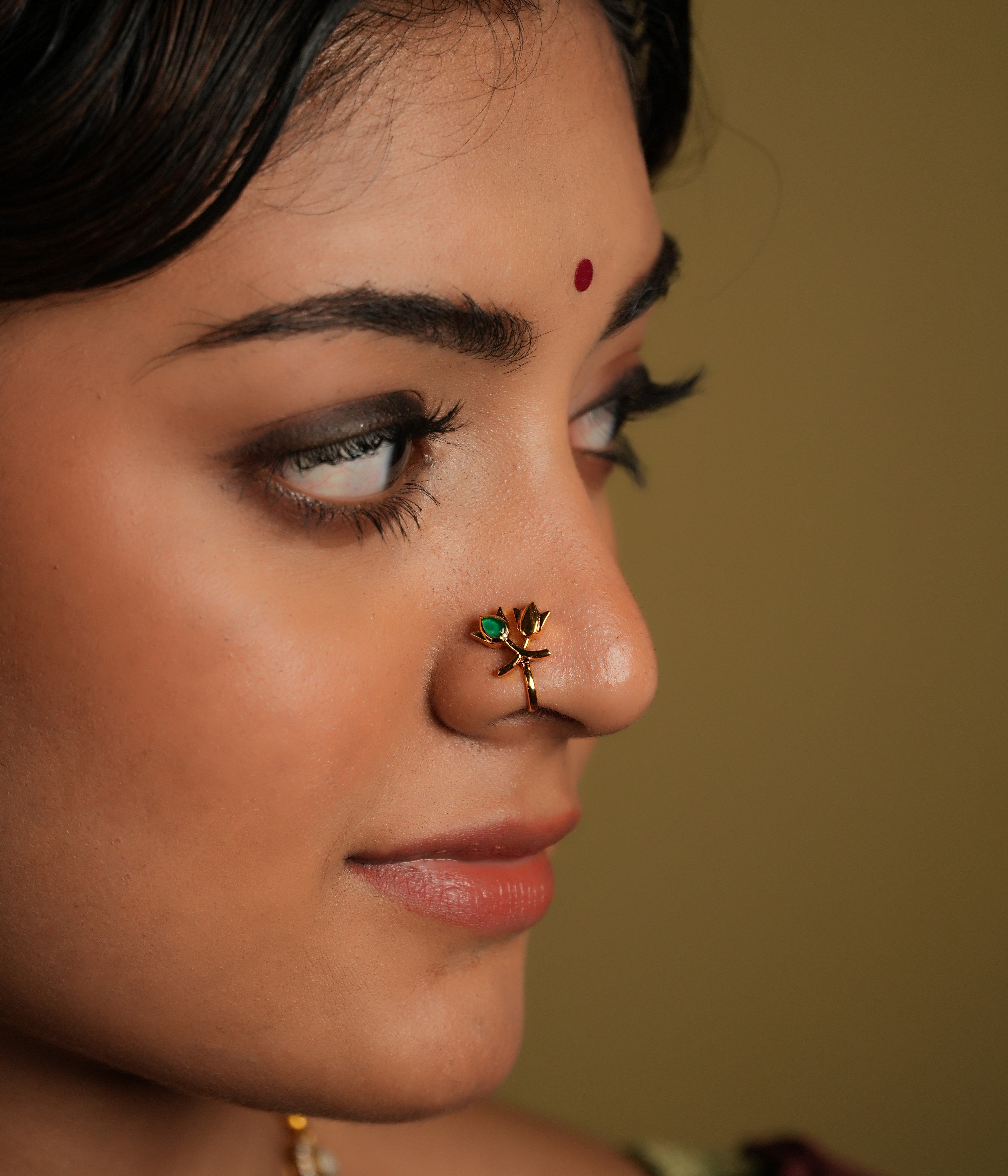 This beautiful nose pin is a blend of traditional artistry and modern design, crafted from 925 sterling silver, ensuring both durability and elegance. It features a stunning kundan stone at its center, which is known for its intricate setting and radiant shine. The lotus-shaped design adds a touch of grace, symbolizing purity and beauty.