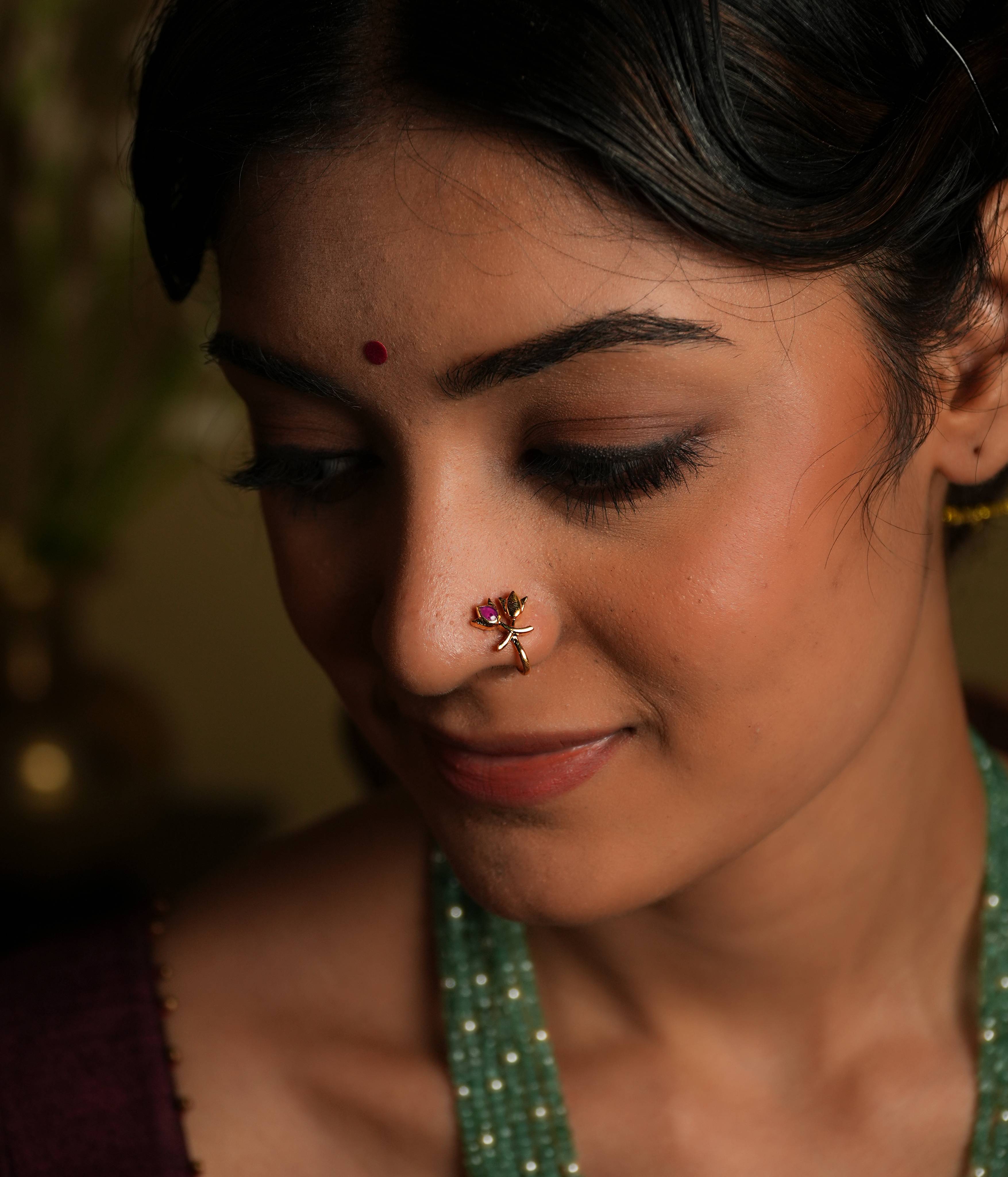 92.5 silver gold plated Petals of serenity, a delicate bloom... This minimal nose stud, featuring a double lotus bud
motif, shines with understated elegance. A subtle pink Kundan accent adds a touch of
natural beauty, evoking the peacefulness of a lotus flower. A tiny, timeless treasure that
exudes subtle sophistication.