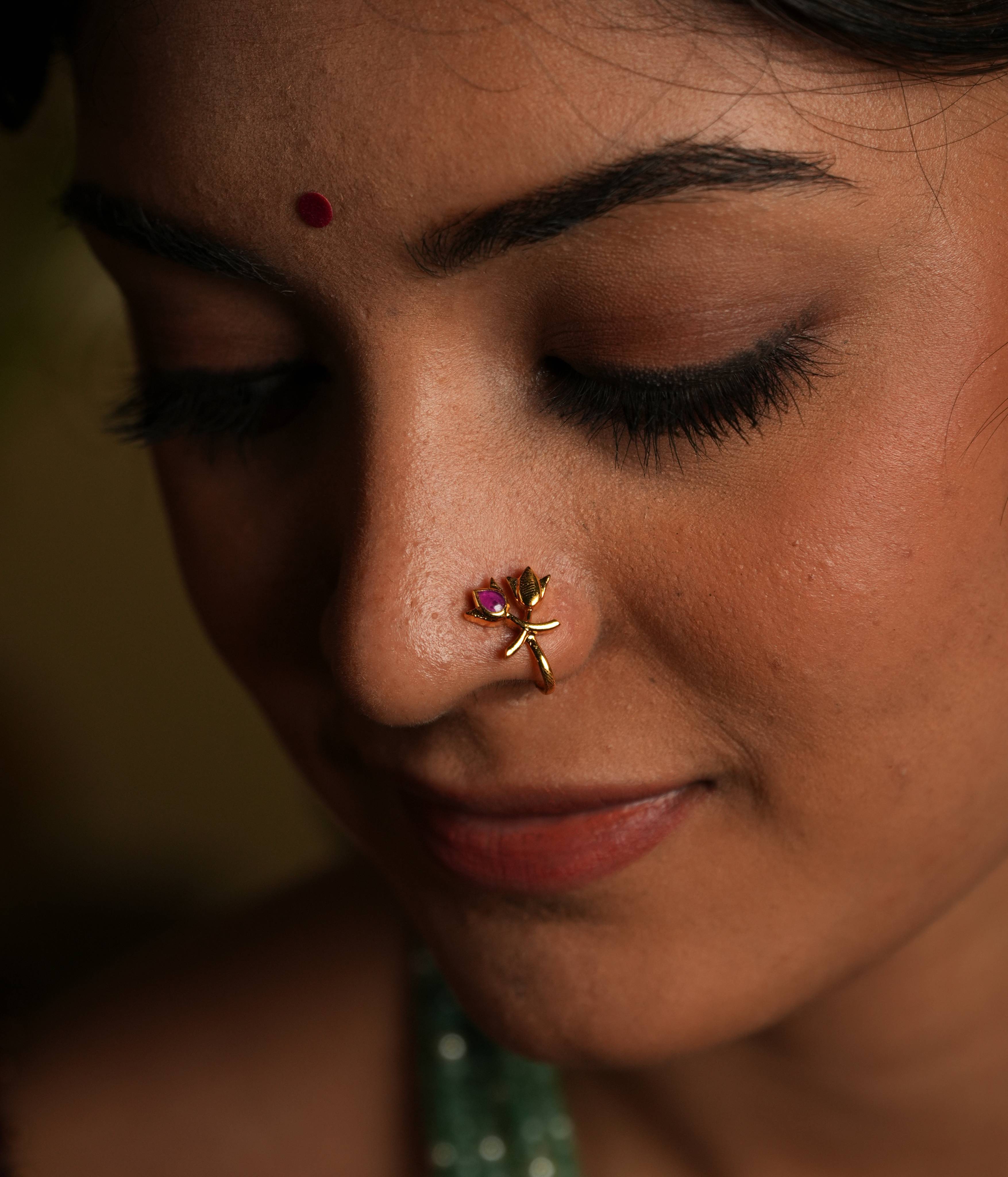 92.5 silver gold plated Petals of serenity, a delicate bloom... This minimal nose stud, featuring a double lotus bud
motif, shines with understated elegance. A subtle pink Kundan accent adds a touch of
natural beauty, evoking the peacefulness of a lotus flower. A tiny, timeless treasure that
exudes subtle sophistication.