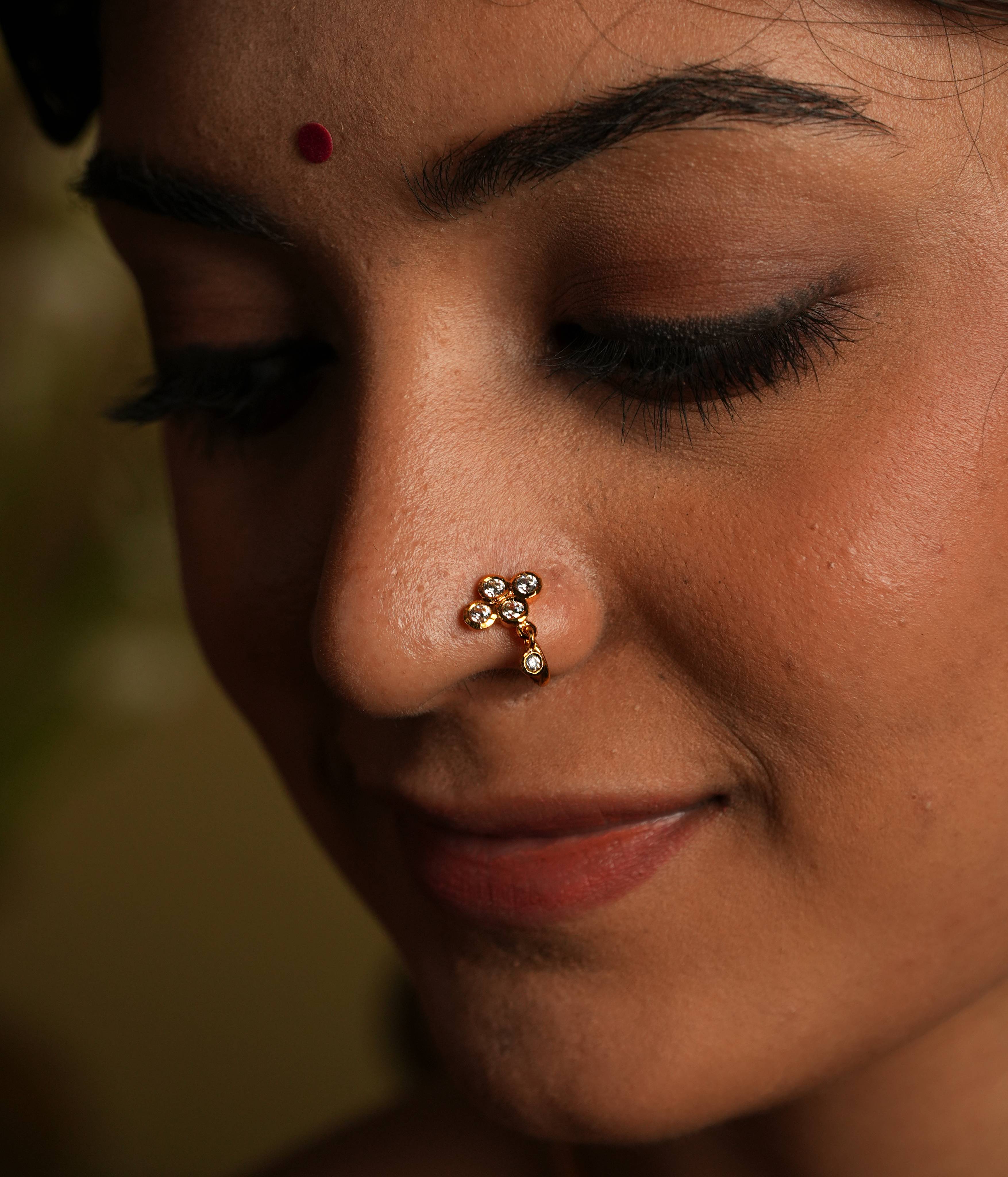 92.5 silver gold plated. This minimal nose stud shines with understated elegance,
featuring a moissanite set stone. A dangling moissanite drop adds a touch of delicate charm,
inspired by vintage Chettinad design language. A tiny, timeless treasure that exudes refined
sophistication.