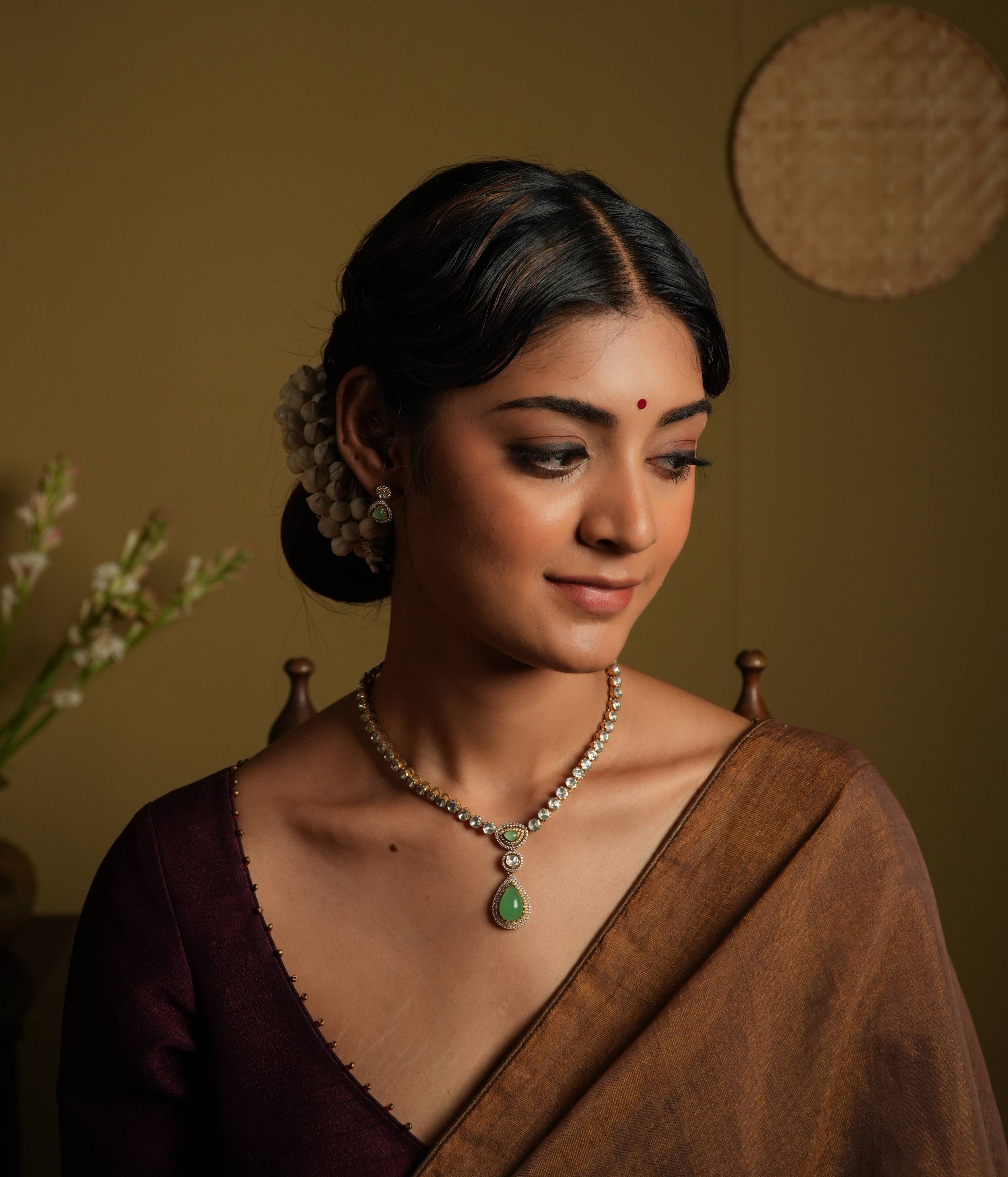 92.5 silver with gold plating This minimal yet statement polki set necklace
shines with sleek sophistication, arranged in a single line. A green gemstone teardrop
pendant, lined with moissanite, adds a touch of luxurious whimsy, creating a truly
show-stopping piece