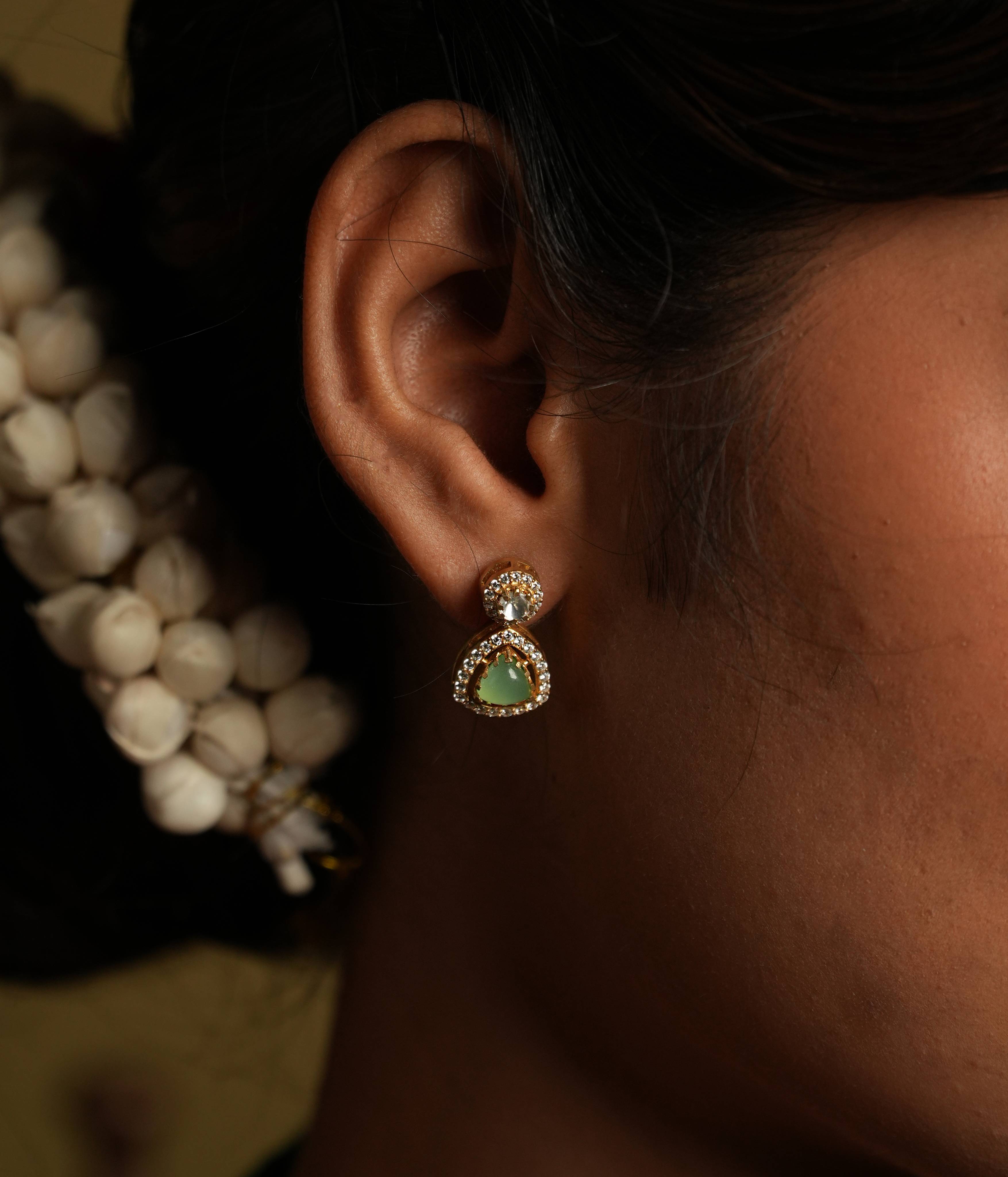 92.5 silver with gold plating charm... This minimal ear stud shines with understated
sophistication, featuring a polki attachment centre. A green gemstone drop adds a touch of
delicate whimsy, creating a timeless treasure that exudes refined beauty. Perfect for
everyday luxury.