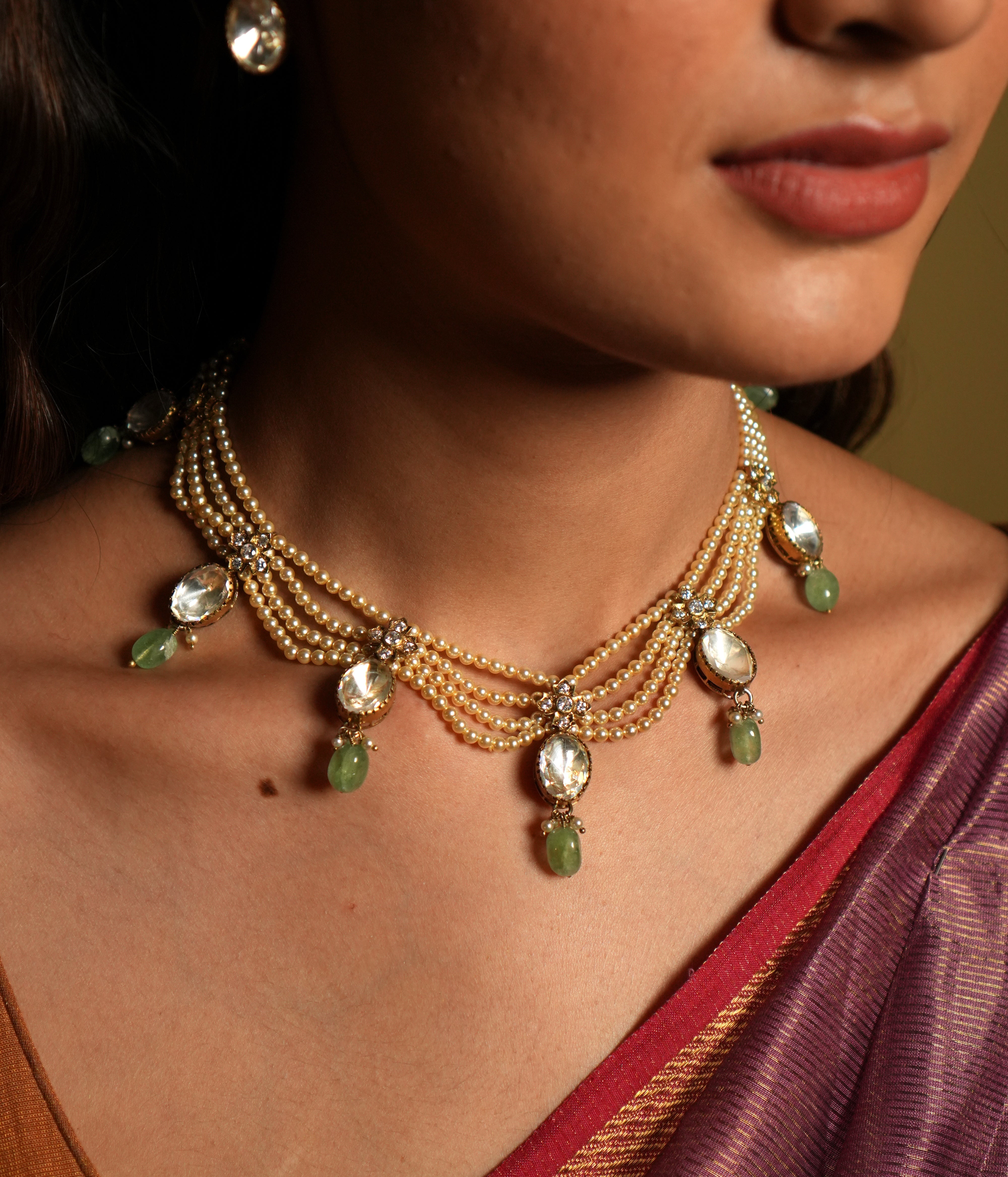 Elevate your traditional attire with this exquisite Moissanite Necklace Set, crafted from 92.5 sterling silver and finished with a rich 22-carat gold plating. The necklace features radiant moissanite stones paired with delicate green gemstone drops, adding a refreshing touch of color and elegance.