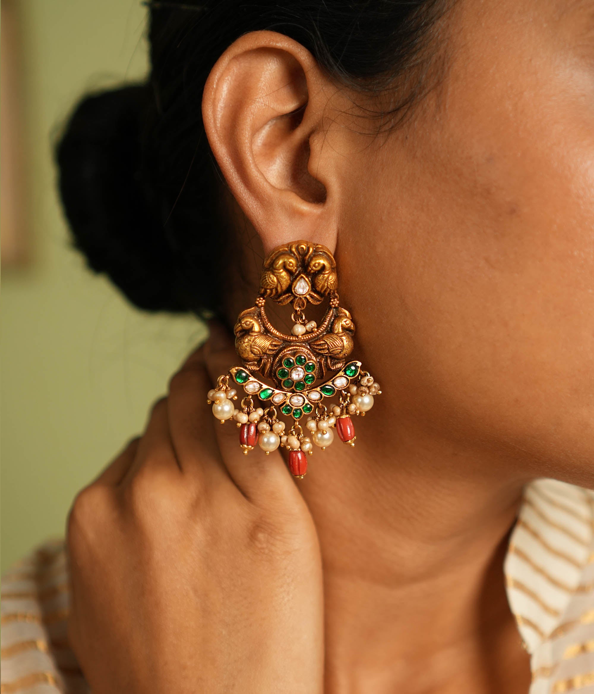 Exquisite gold-plated silver Chandbali earrings featuring a graceful peacock design, adorned with vibrant green Kundan stones, shimmering white Kundan stones, delicate pearls, and striking red beads, blending traditional elegance with timeless craftsmanship