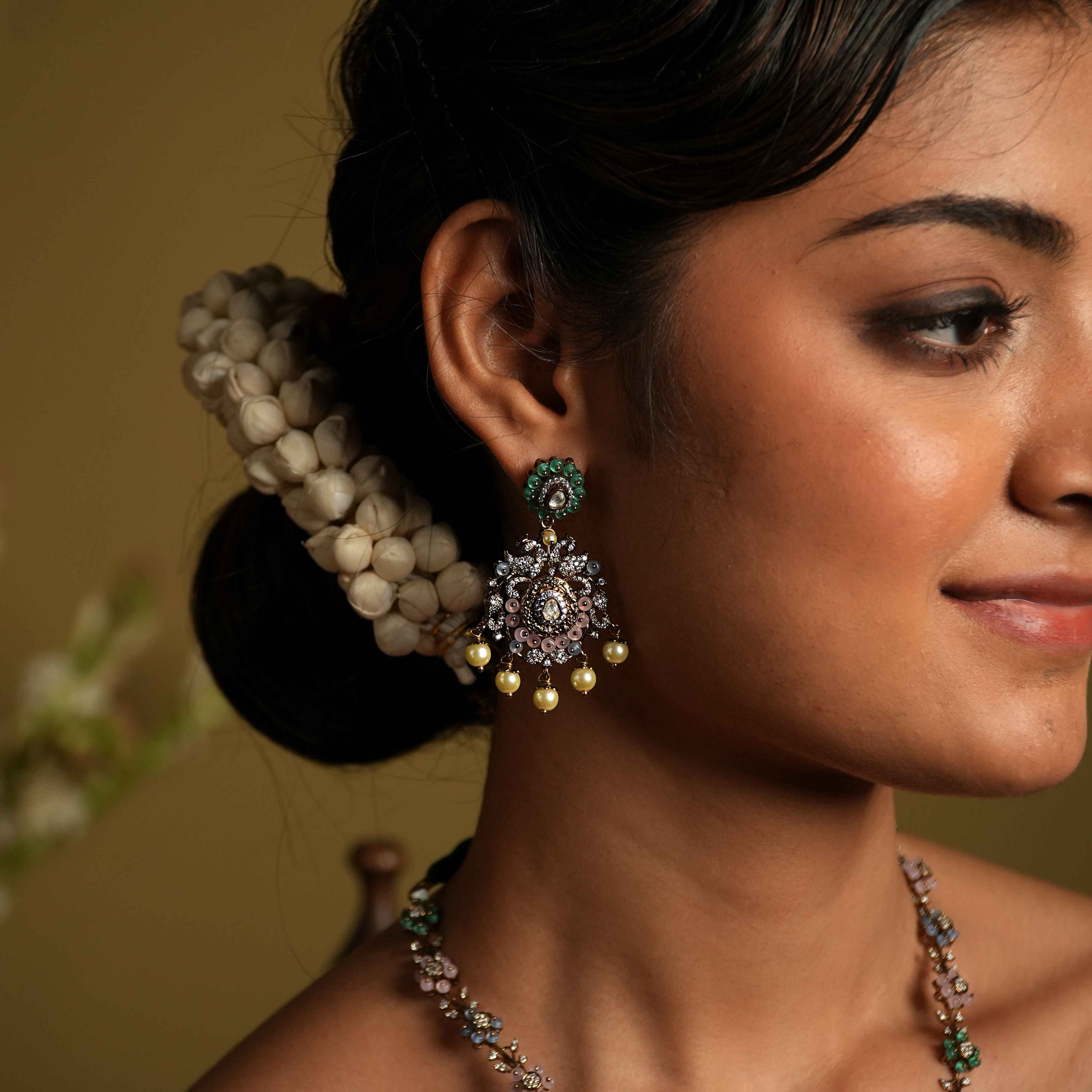 These intricate floral Chandbali earrings, crafted from 92.5 sterling silver and featuring Bombay screw fastenings, showcase moissanite and green gemstones, with show-stopping double peacock moissanite set danglings, elevating the piece to new heights of glamour and refinement.