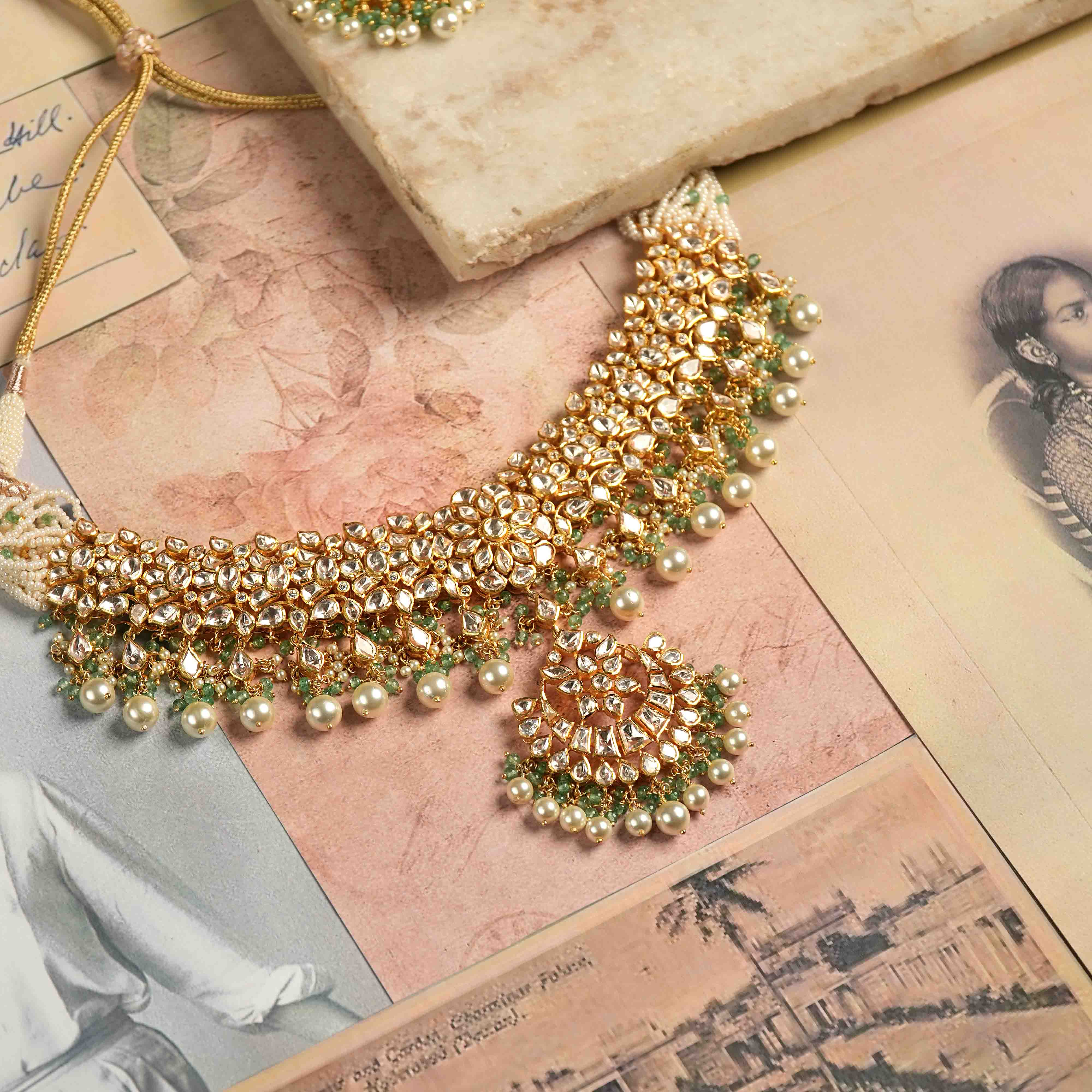 A handcrafted 92.5 sterling silver and 22ct gold-plated polki jadau choker, featuring polki stones, CZ stones, and green gemstones, with elegant pearl dangles, evoking the opulence of vintage Rajput jewelry and embodying majestic heritage.