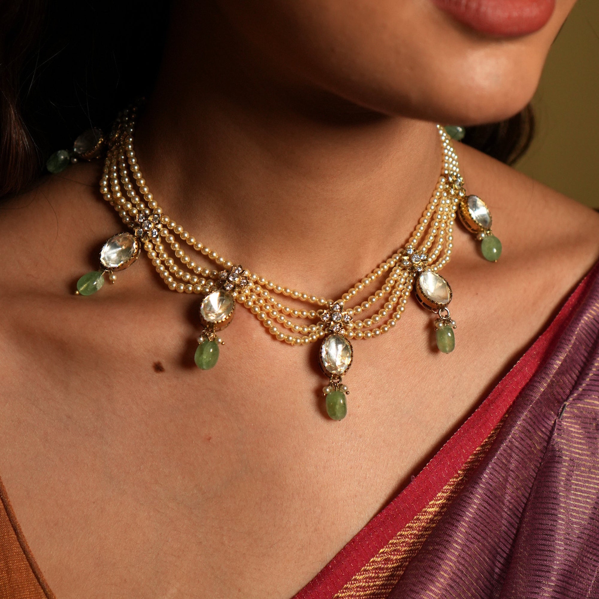 Close-up of a woman wearing a detailed necklace with green and gold beads.