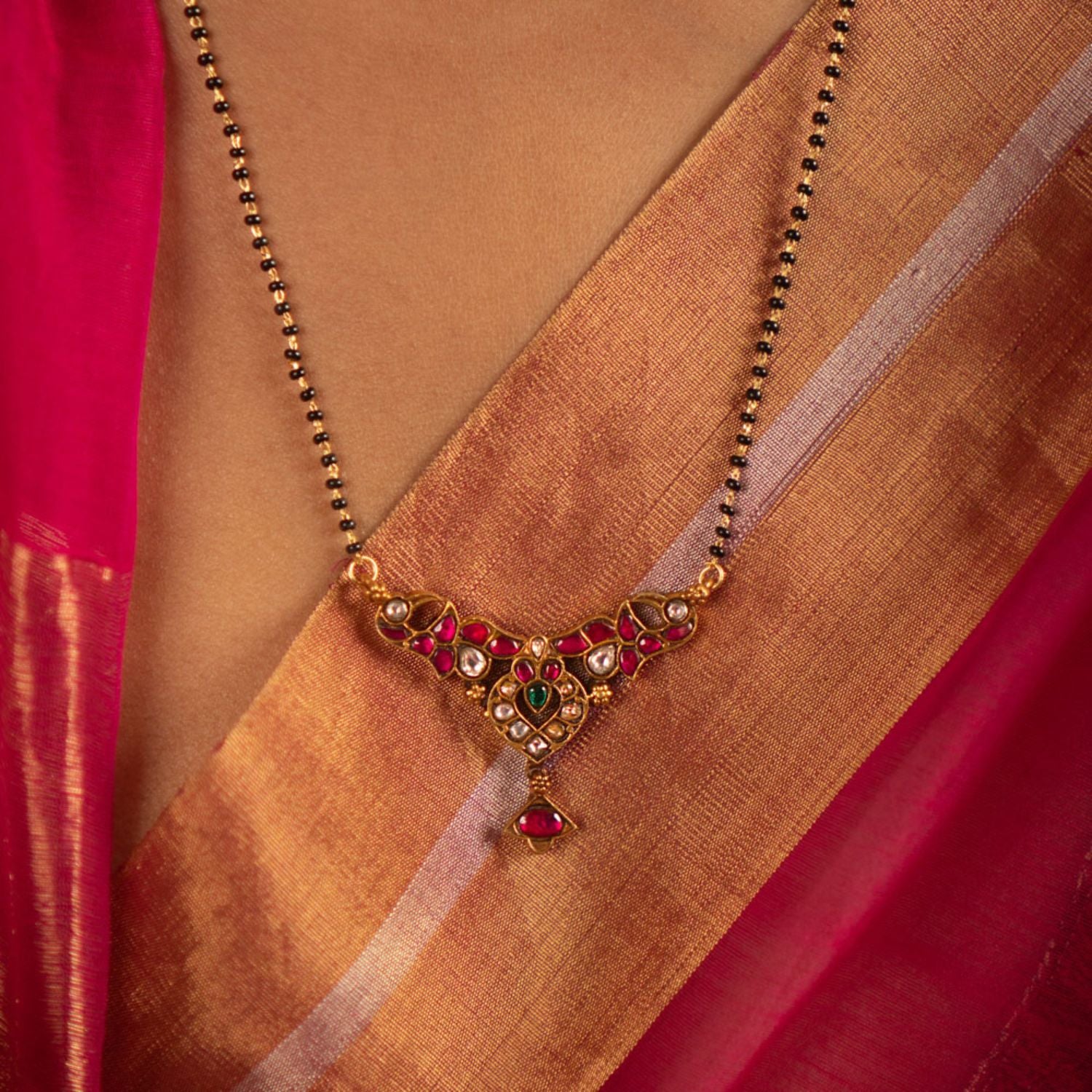 The Bhoomi Mangalsutra, crafted in gold-plated silver, showcases intricate Kundan peacock motifs that capture the vibrancy of Indian heritage. Adorned with red, white, and green Kundan stones along with delicate freshwater pearls, this piece blends classic beauty with understated elegance.