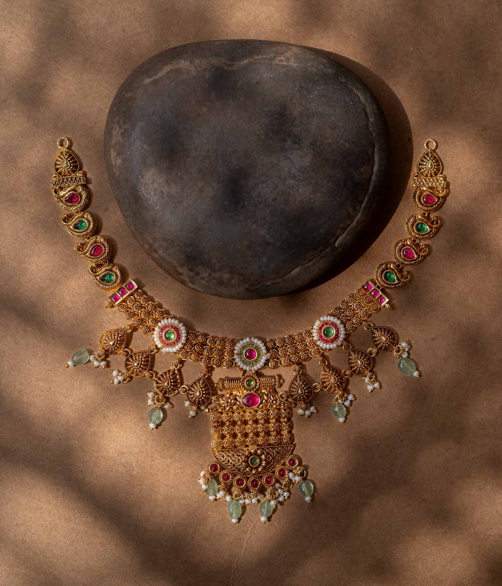 A 92.5 sterling silver Samhita Lakshmi Heritage Necklace with antique gold filigree, vibrant ruby and emerald accents, soft green drops, a divine Lakshmi pendant, and a pearl-laden fringe, echoing temple artistry for grand celebrations.