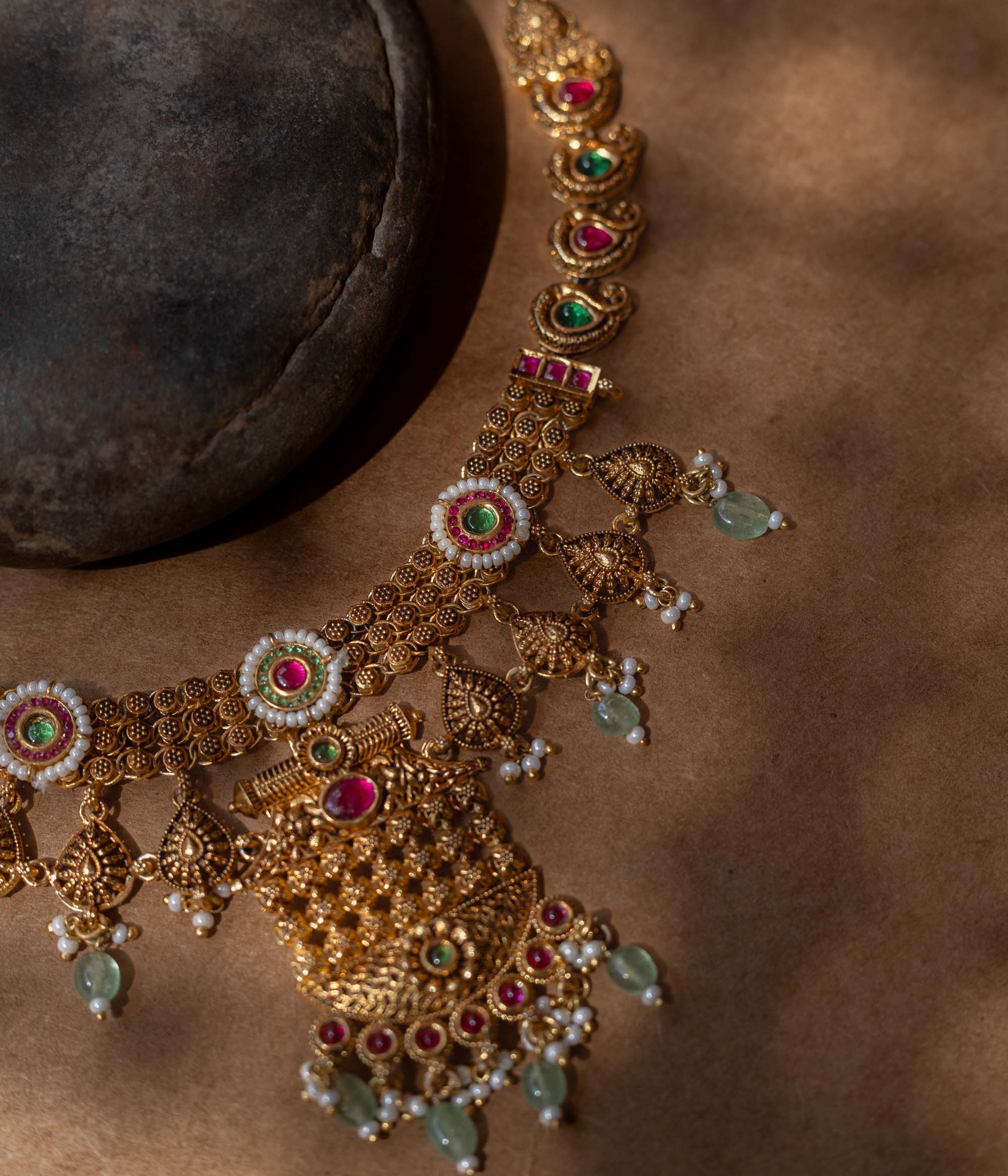 A 92.5 sterling silver Samhita Lakshmi Heritage Necklace with antique gold filigree, vibrant ruby and emerald accents, soft green drops, a divine Lakshmi pendant, and a pearl-laden fringe, echoing temple artistry for grand celebrations.