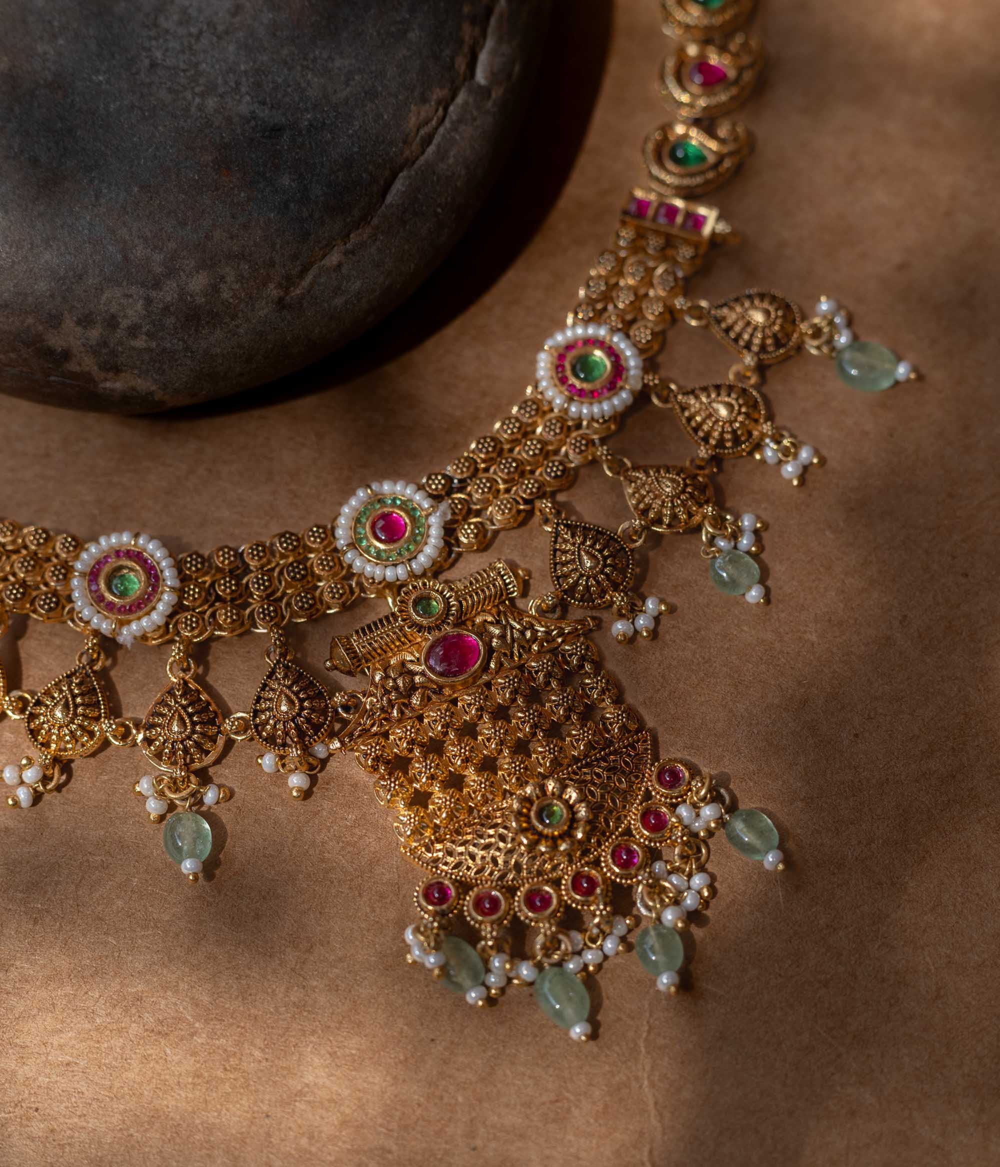 A 92.5 sterling silver Samhita Lakshmi Heritage Necklace with antique gold filigree, vibrant ruby and emerald accents, soft green drops, a divine Lakshmi pendant, and a pearl-laden fringe, echoing temple artistry for grand celebrations.
