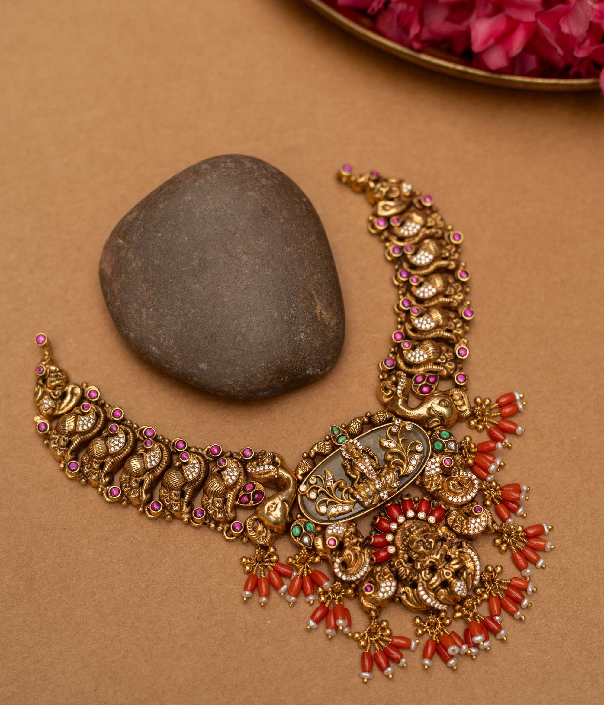 Elevate your traditional ensemble with the 92.5 sterling silver Divine Royal Heritage Choker, a magnificent piece of temple jewellery with an antique gold finish. This ornate choker features a central Lakshmi motif amidst intricate engravings, surrounded by elephants, peacocks, and mythological figures, accented with red coral drops, kundan stones, and delicate pearls, embodying spiritual grace and royal grandeur for weddings, poojas, and festive occasions.