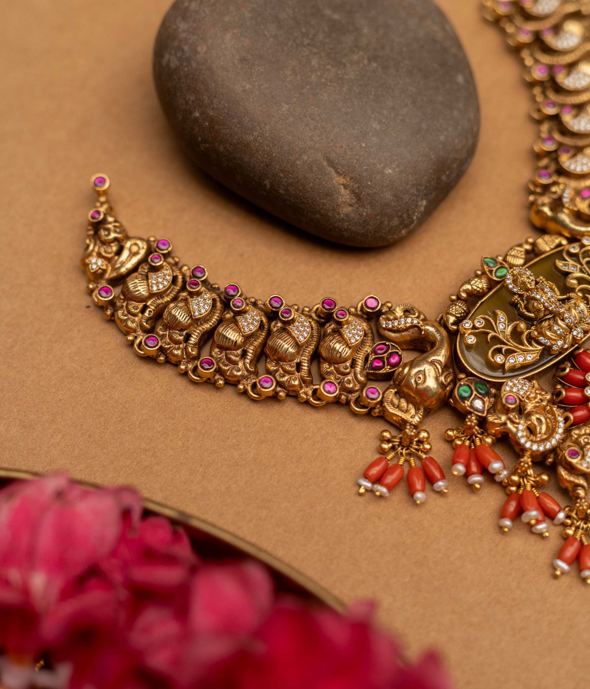 Elevate your traditional ensemble with the 92.5 sterling silver Divine Royal Heritage Choker, a magnificent piece of temple jewellery with an antique gold finish. This ornate choker features a central Lakshmi motif amidst intricate engravings, surrounded by elephants, peacocks, and mythological figures, accented with red coral drops, kundan stones, and delicate pearls, embodying spiritual grace and royal grandeur for weddings, poojas, and festive occasions.