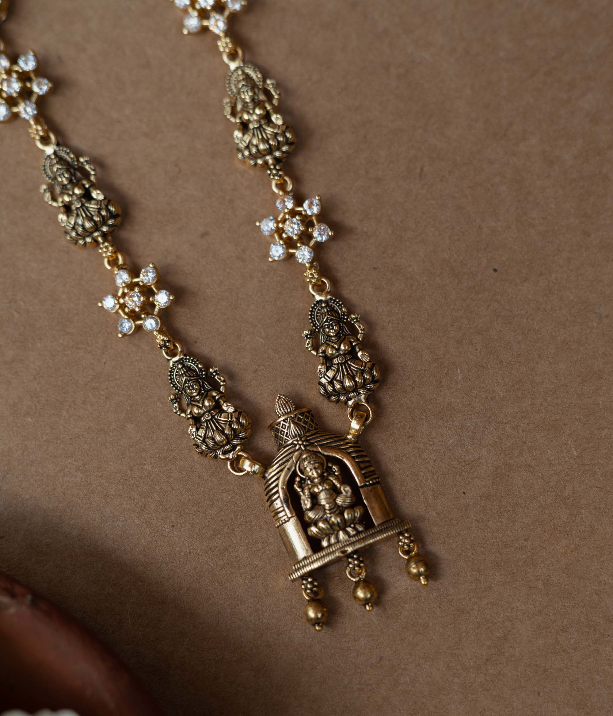 A 92.5 sterling silver Gauri Temple Pendant Necklace, featuring antique-finish Lakshmi motifs, floral crystal links, and a central temple pendant, invoking divine elegance for festive and traditional celebrations.