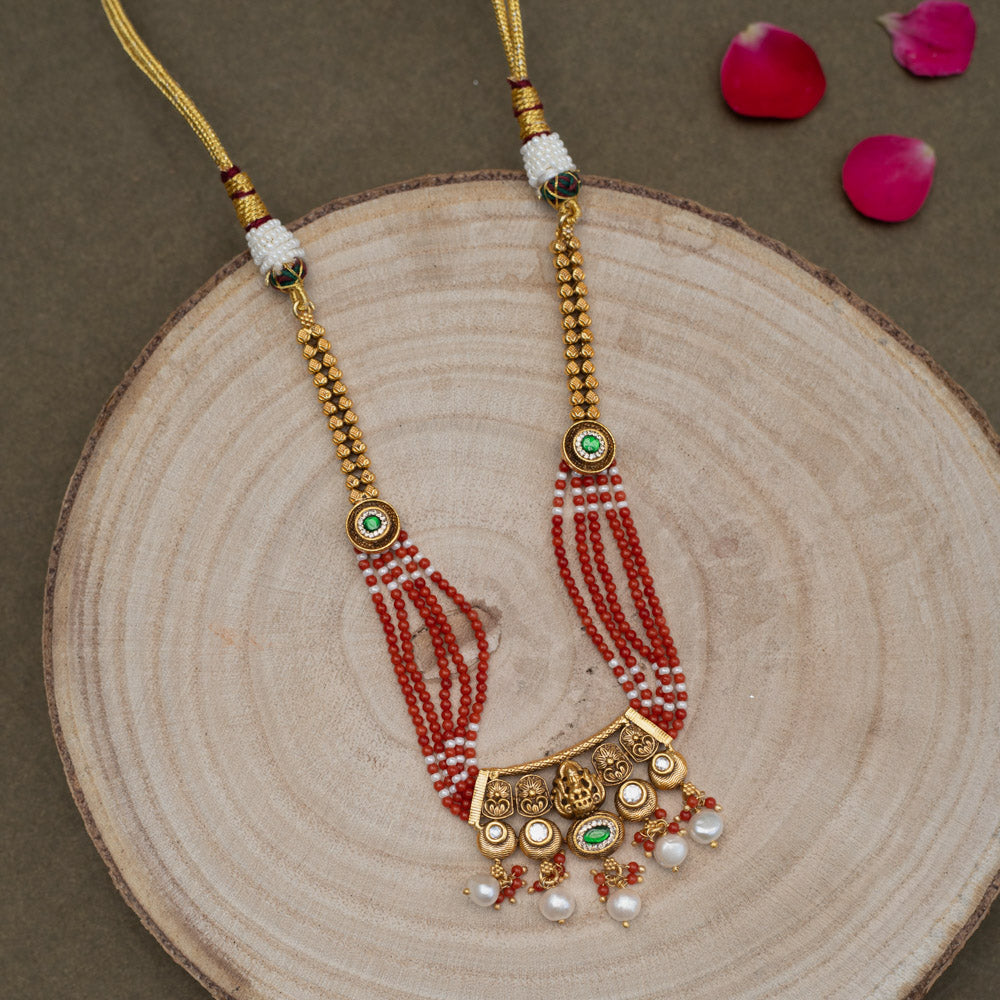 Multi-stranded necklace with vibrant coral and white beads, interspersed with gold-plated 92.5 sterling silver Ganesha motifs and green accents. Ganesha pendant with pearl drops.