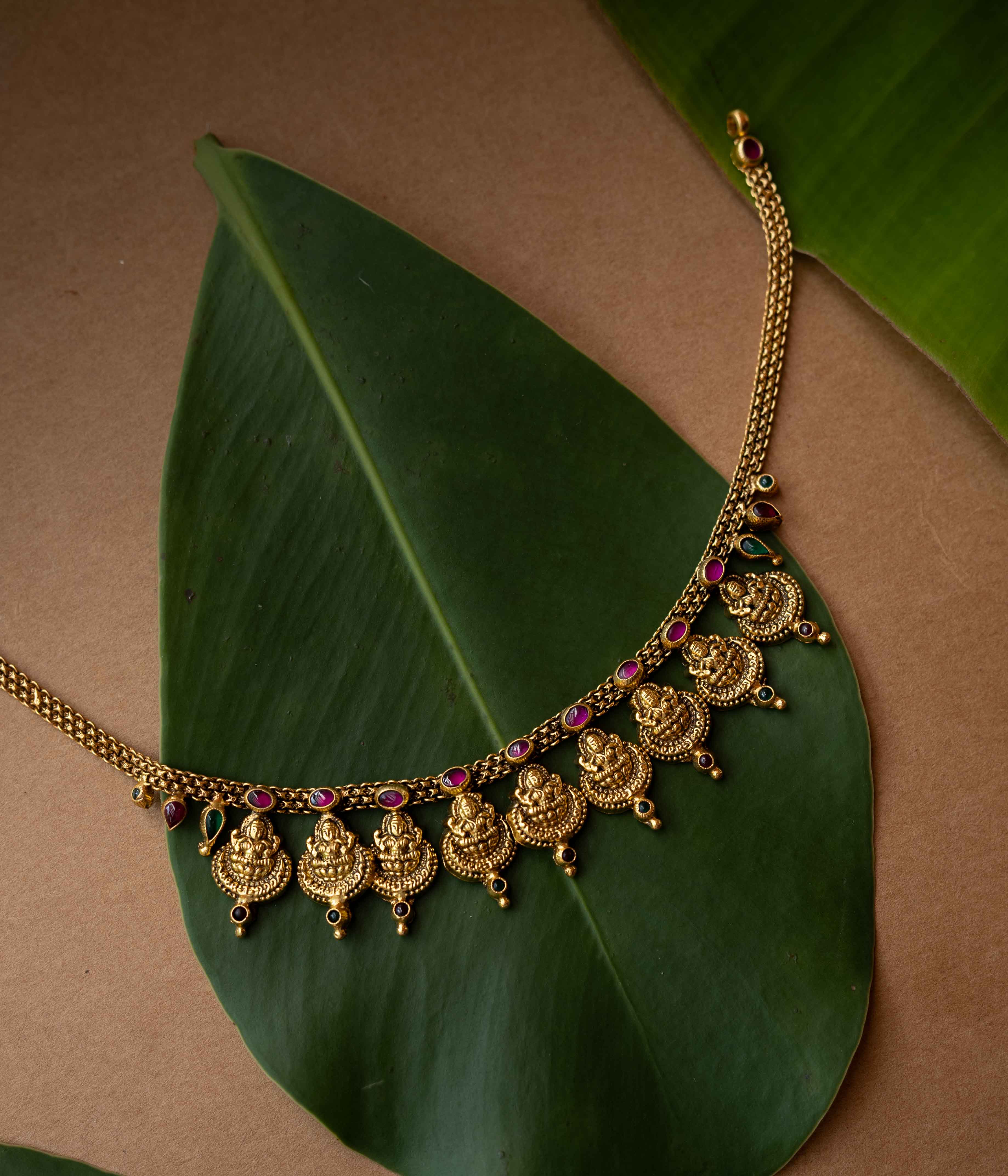 Antique gold temple necklace with multiple Lakshmi motifs and ruby-green accents from Temple Collection.