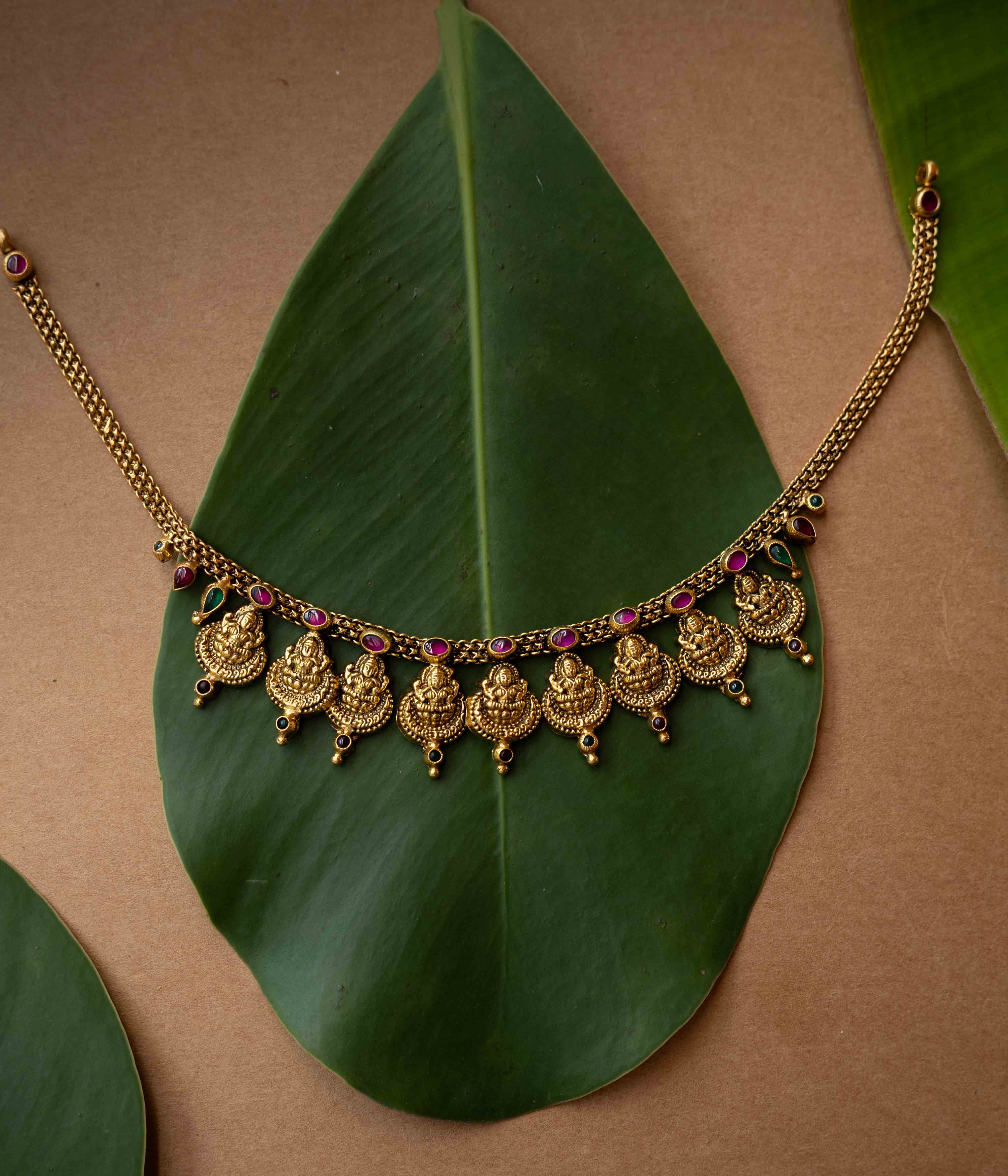 Antique gold temple necklace with multiple Lakshmi motifs and ruby-green accents from Temple Collection.