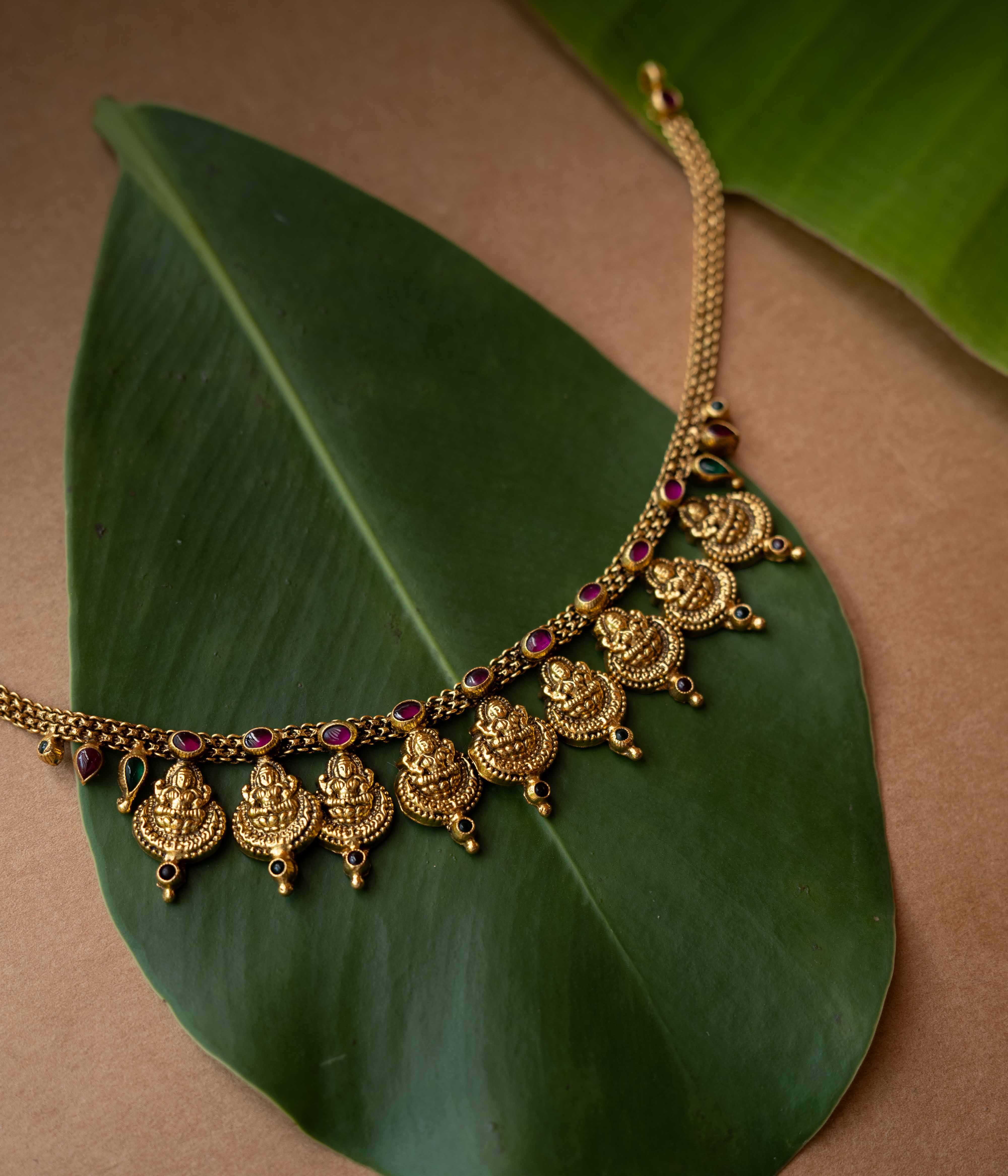 Antique gold temple necklace with multiple Lakshmi motifs and ruby-green accents from Temple Collection.