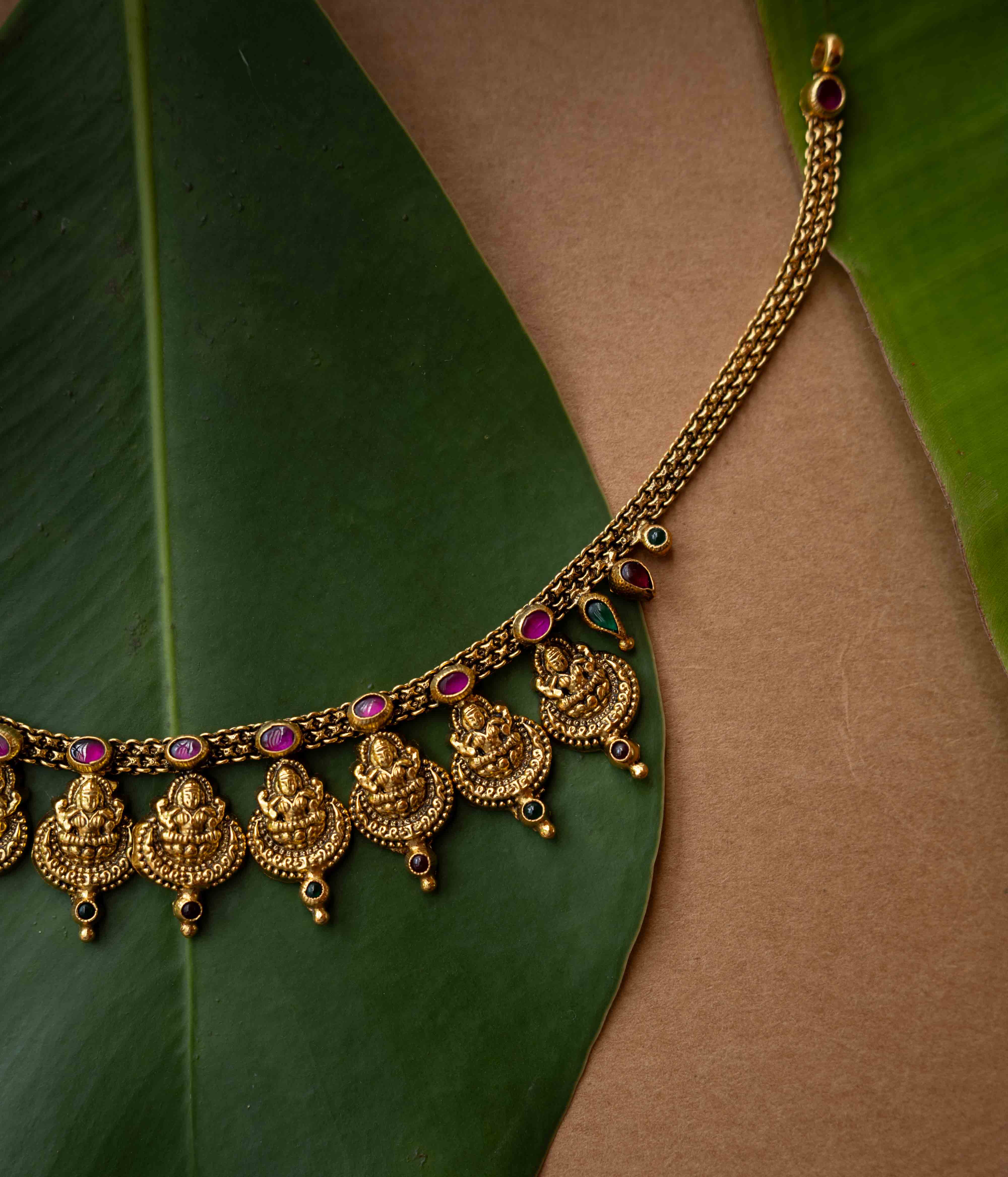 Antique gold temple necklace with multiple Lakshmi motifs and ruby-green accents from Temple Collection.