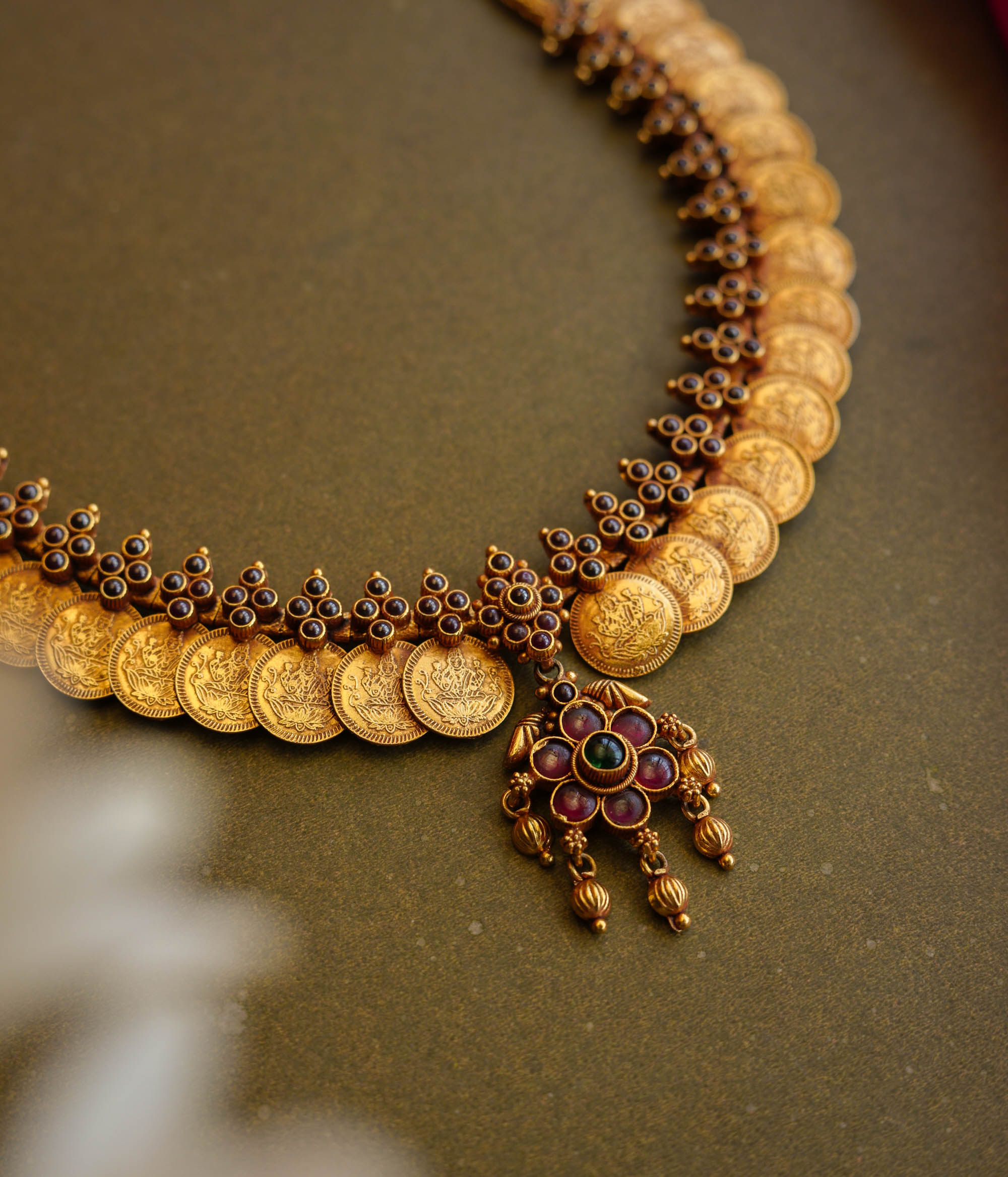 Gold coin motif necklace with red and green stones from Temple Collection.