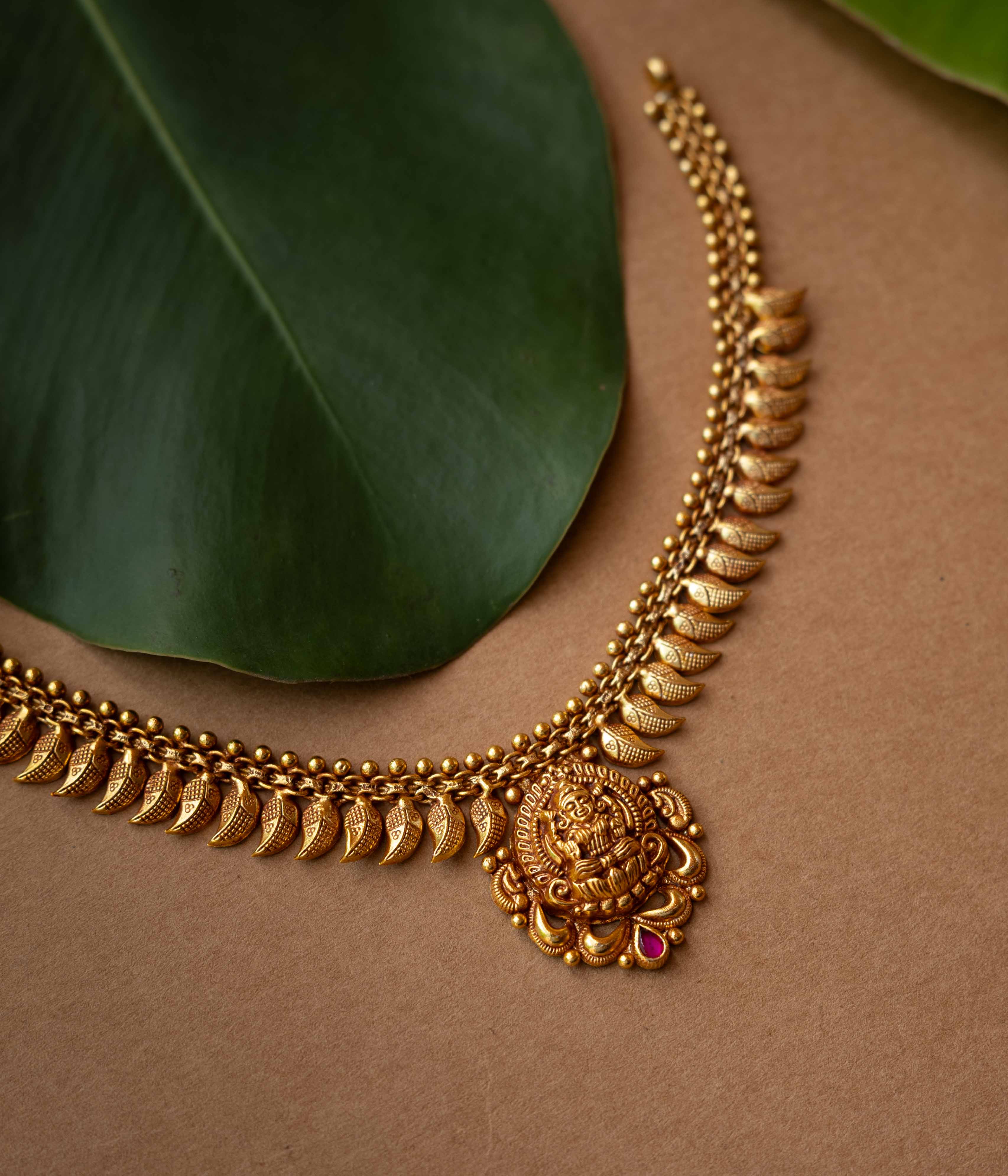 Antique gold necklace with Goddess Lakshmi pendant and crescent motifs from Temple Collection.