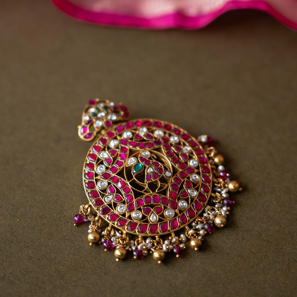 A 92.5 sterling silver piece featuring red and white Kundan stones and pearls, described as a timeless masterpiece adorned with radiant gemstones and intricate gold craftsmanship, echoing the grandeur of heritage and tradition.