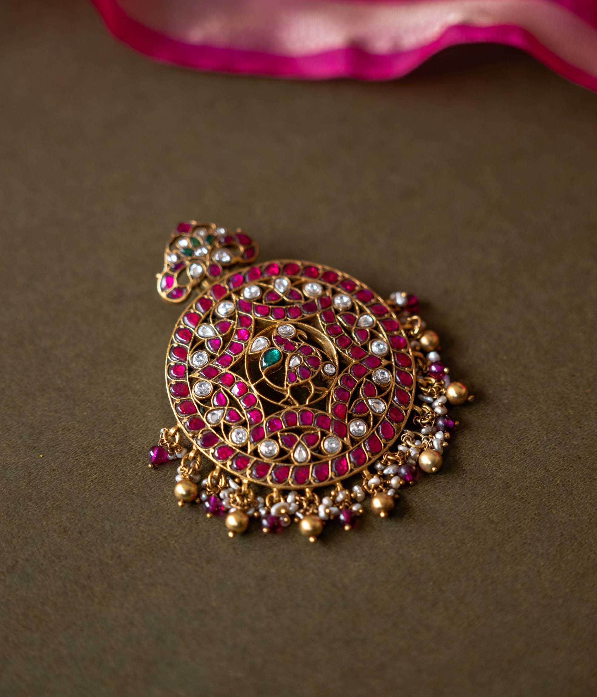 A 92.5 sterling silver piece featuring red and white Kundan stones and pearls, described as a timeless masterpiece adorned with radiant gemstones and intricate gold craftsmanship, echoing the grandeur of heritage and tradition.