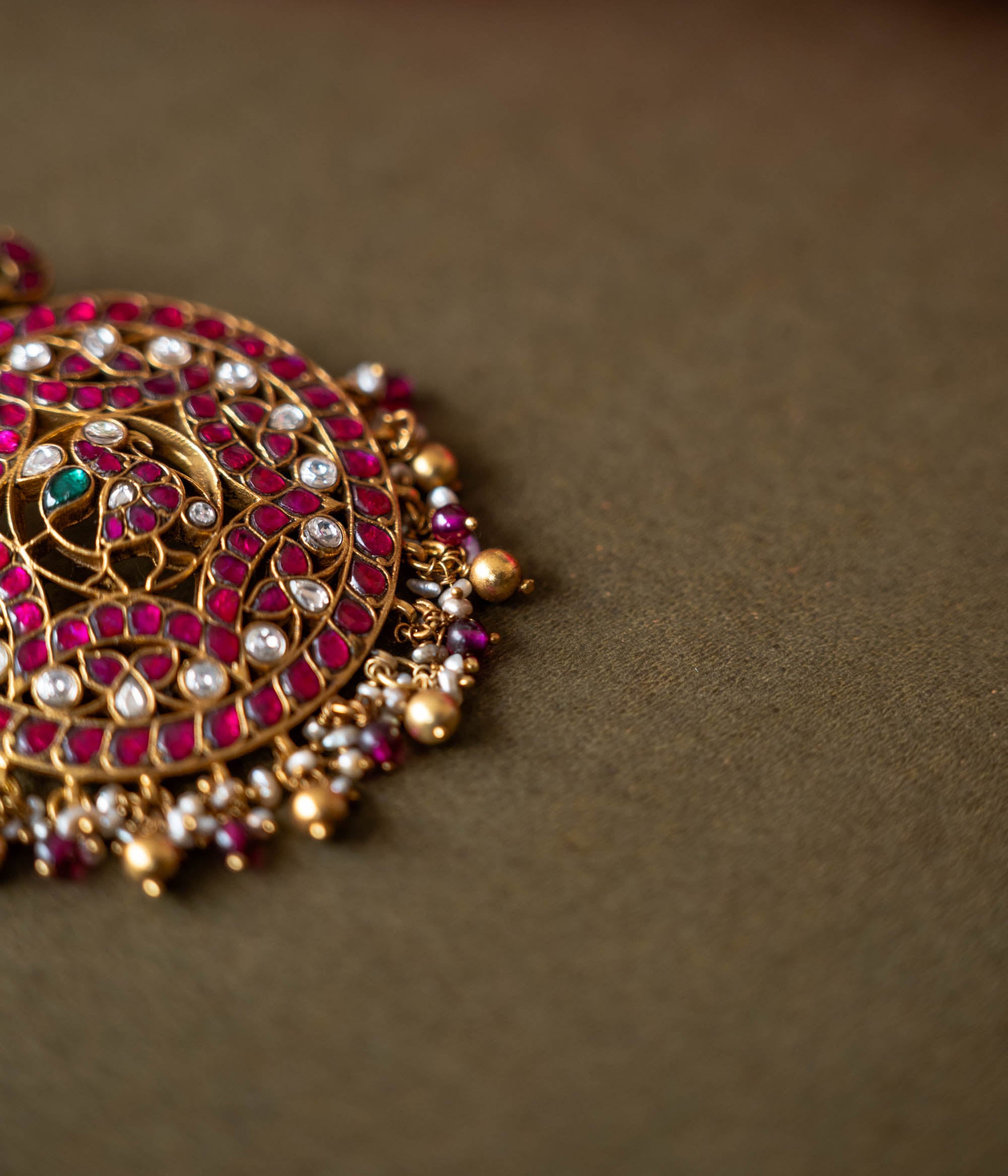 A 92.5 sterling silver piece featuring red and white Kundan stones and pearls, described as a timeless masterpiece adorned with radiant gemstones and intricate gold craftsmanship, echoing the grandeur of heritage and tradition.