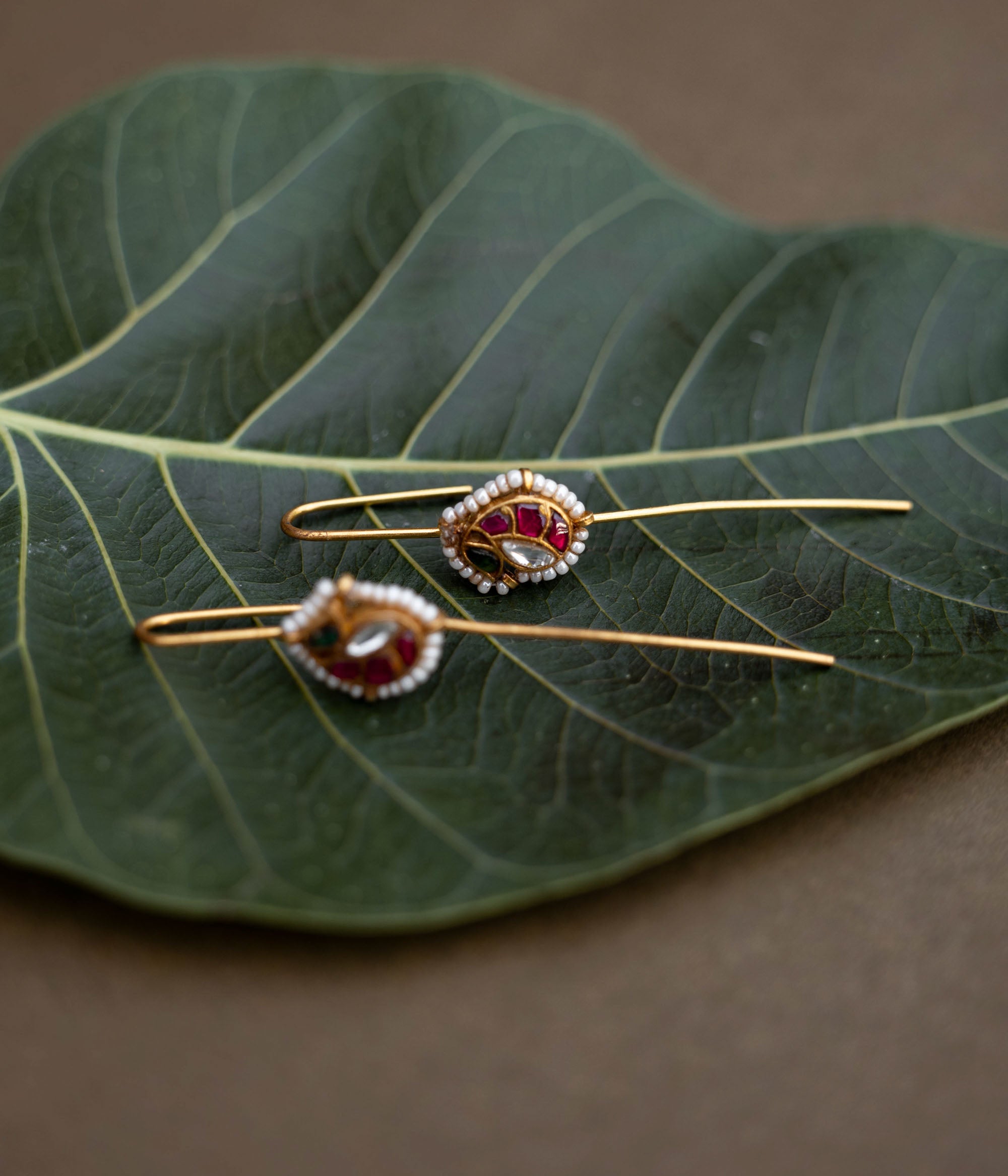 A handcrafted 92.5 sterling silver and 22ct gold-plated bugadi, featuring white, red, and green Kundan stones, pearls, and a pearl-lined finish, embodying grace and heritage charm.