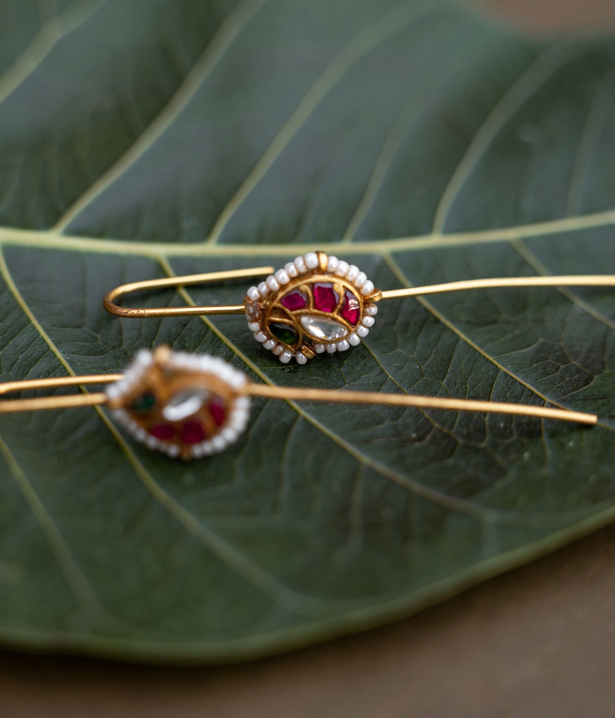 A handcrafted 92.5 sterling silver and 22ct gold-plated bugadi, featuring white, red, and green Kundan stones, pearls, and a pearl-lined finish, embodying grace and heritage charm.