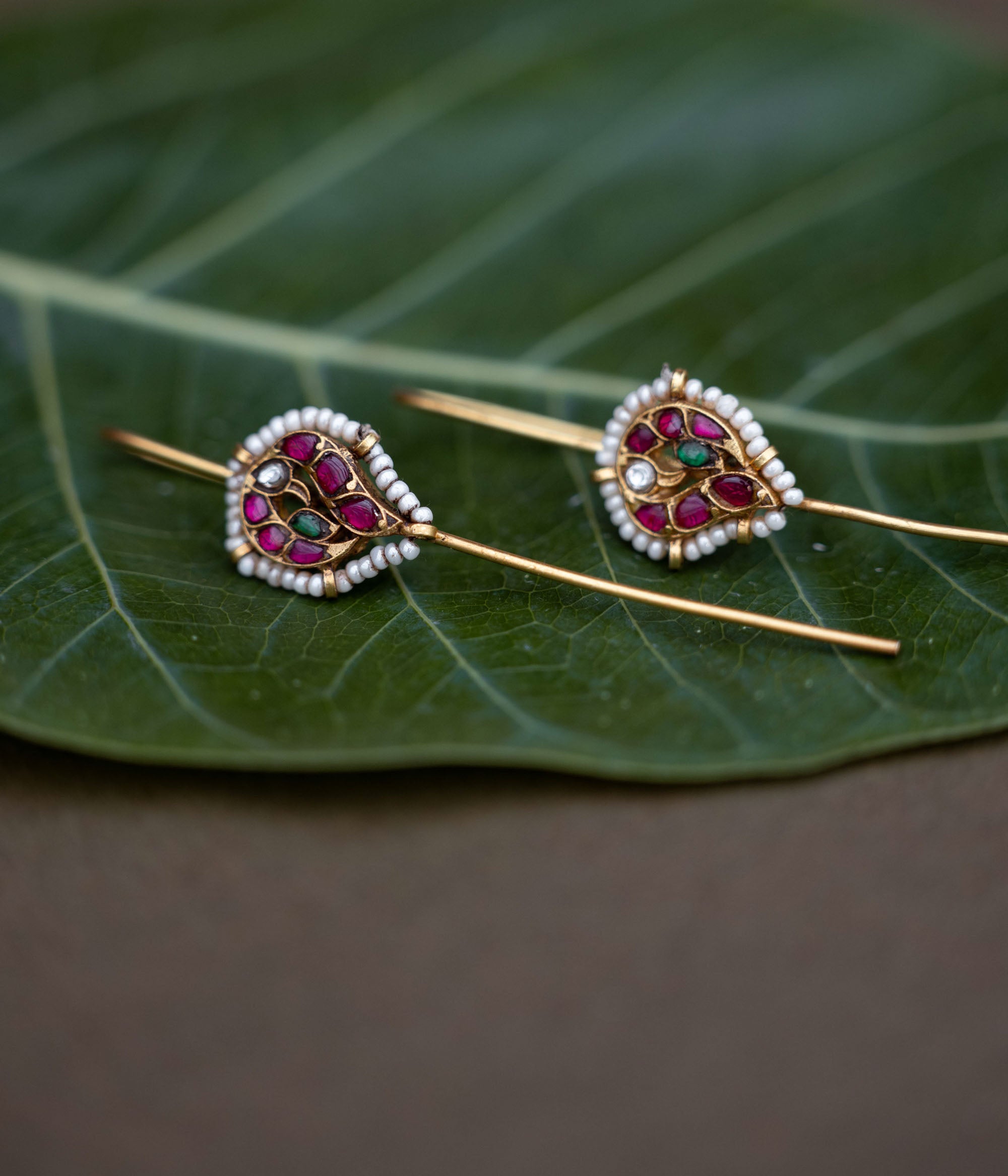 A handcrafted 92.5 sterling silver and 22ct gold-plated bugadi, featuring white, red, and green Kundan stones, pearls, and a delicate pearl border, embodying grace and heritage with every detail.