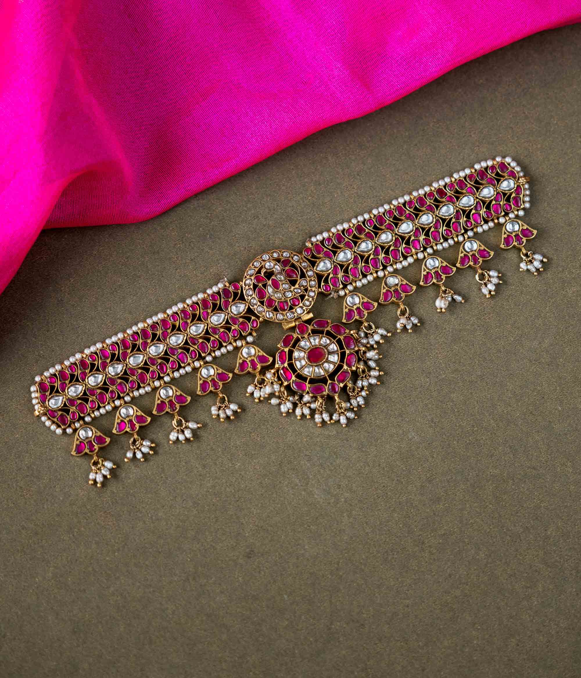 A 92.5 sterling silver choker, adorned with dazzling polki stones, red Kundan stones, and pearl droplets, embodying regal charm and timeless grace.