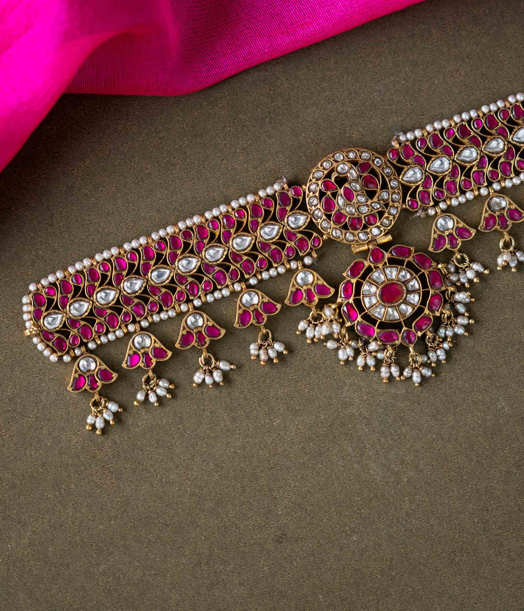 A 92.5 sterling silver choker, adorned with dazzling polki stones, red Kundan stones, and pearl droplets, embodying regal charm and timeless grace.